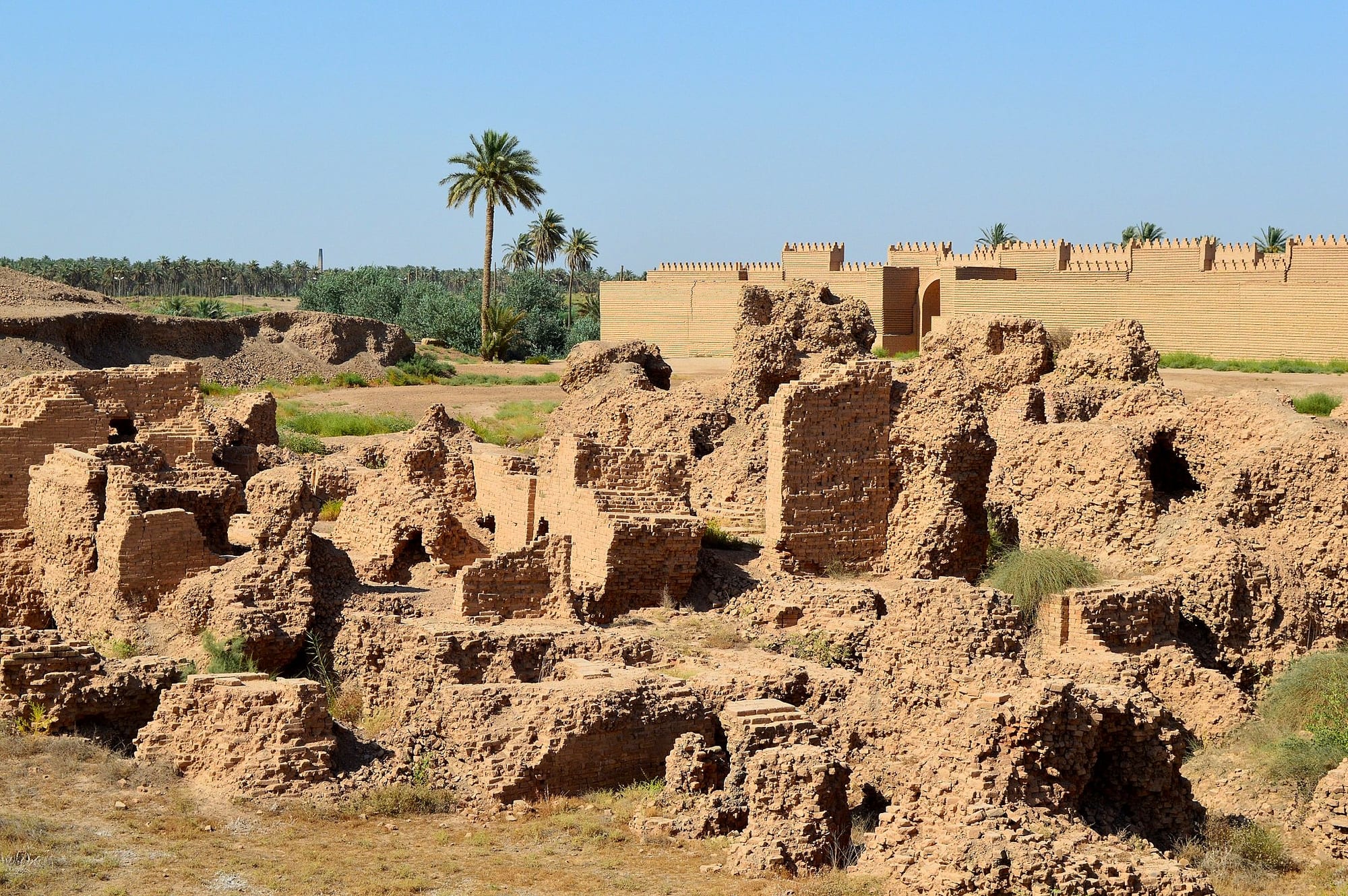 Reconstructed mud-brick walls and foundations of an ancient city on a dusty plain
