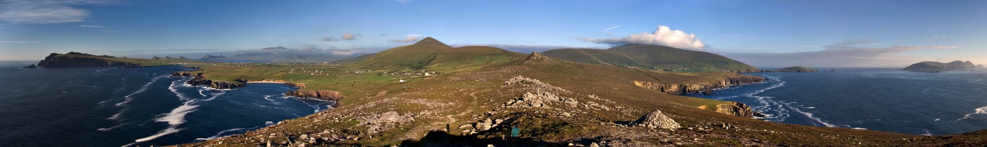 A panoramic view of green Atlantic-facing hills, a curving beach, and islands offshore