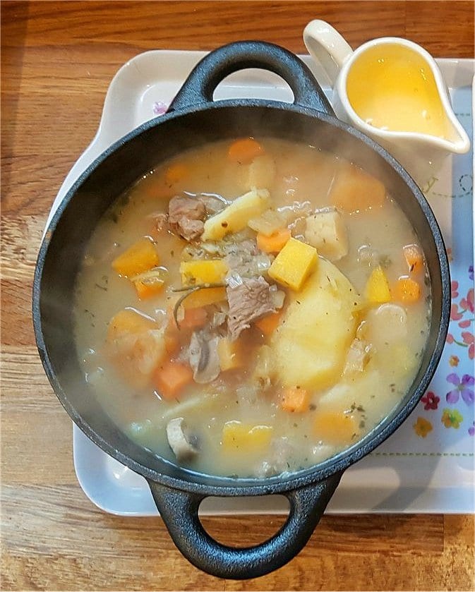 A bowl of stew with chunks of meat, potatoes and vegetables