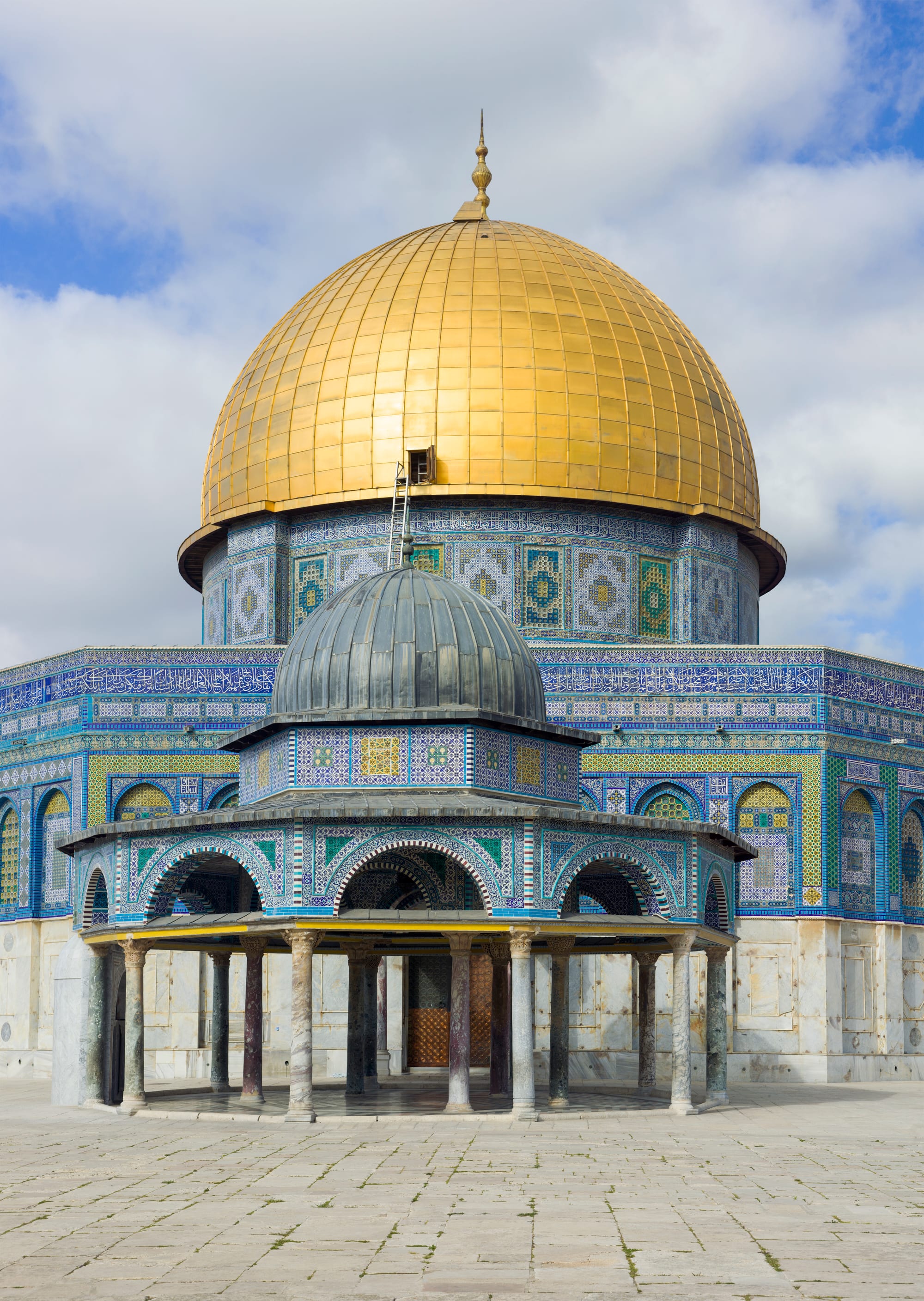 A golden-domed octagonal shrine with blue-tiled walls on a broad stone platform