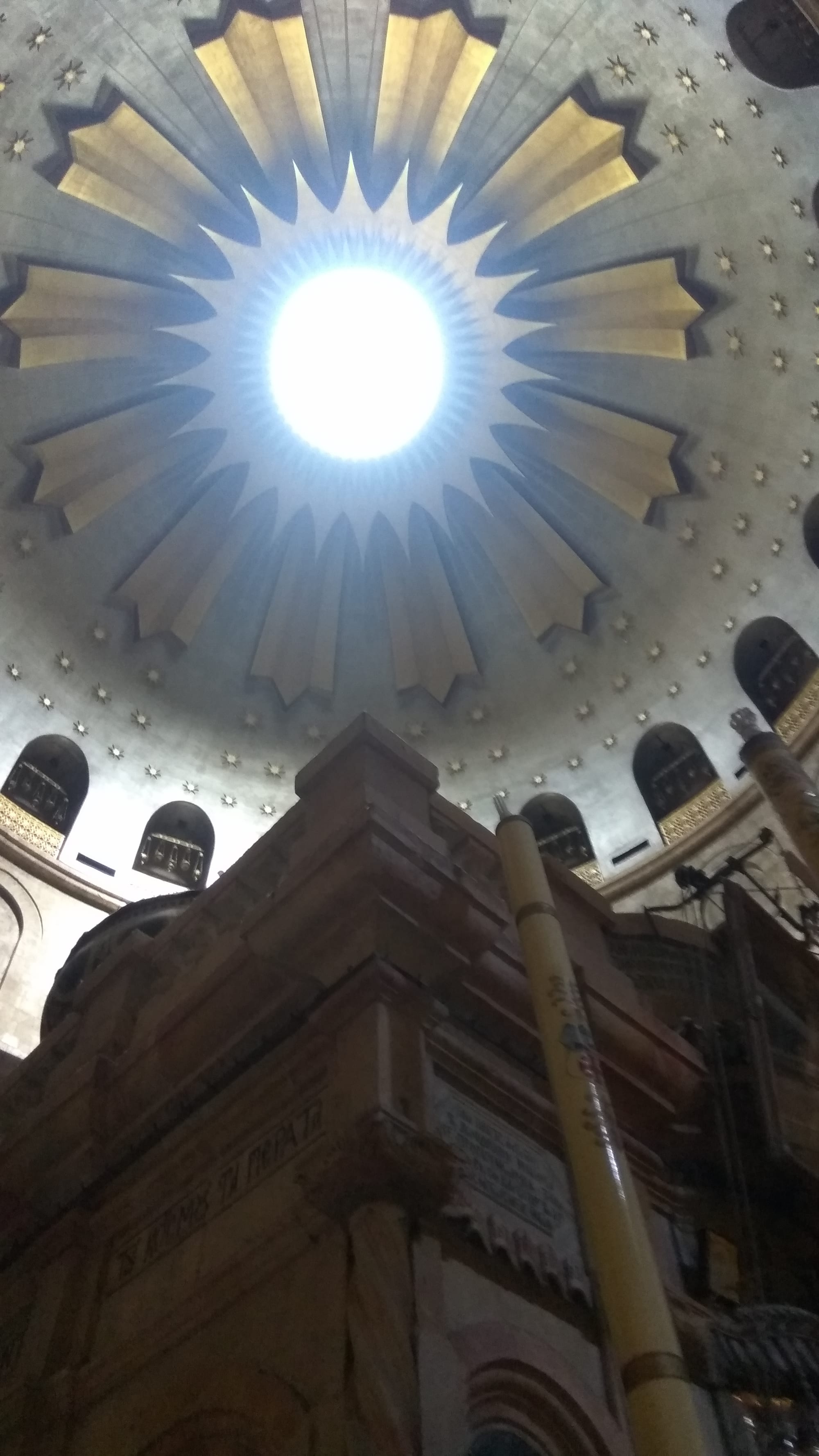 A domed rotunda with a small ornate shrine beneath it, lit by shafts of light