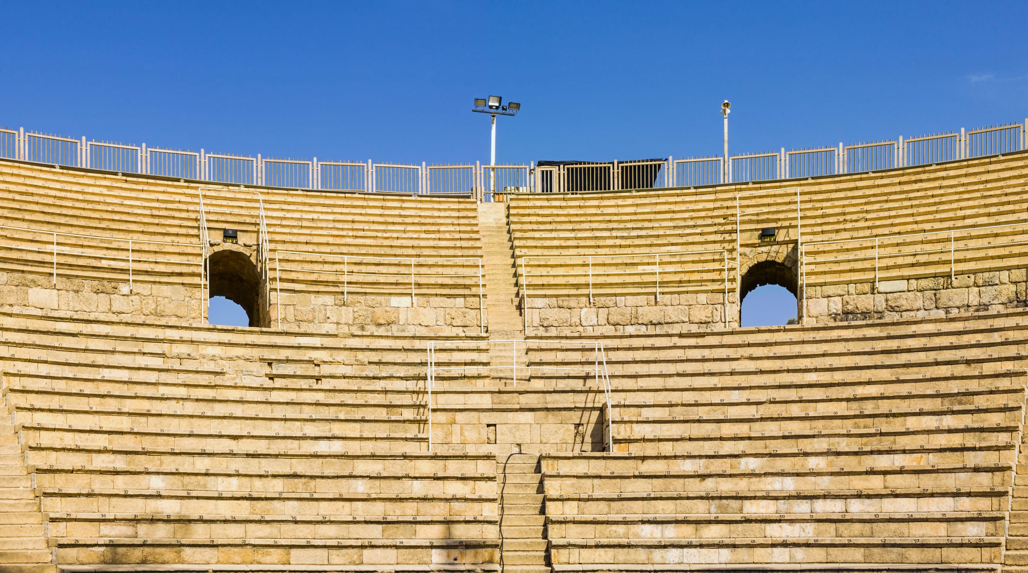 A restored Roman theatre of stone seating facing the sea
