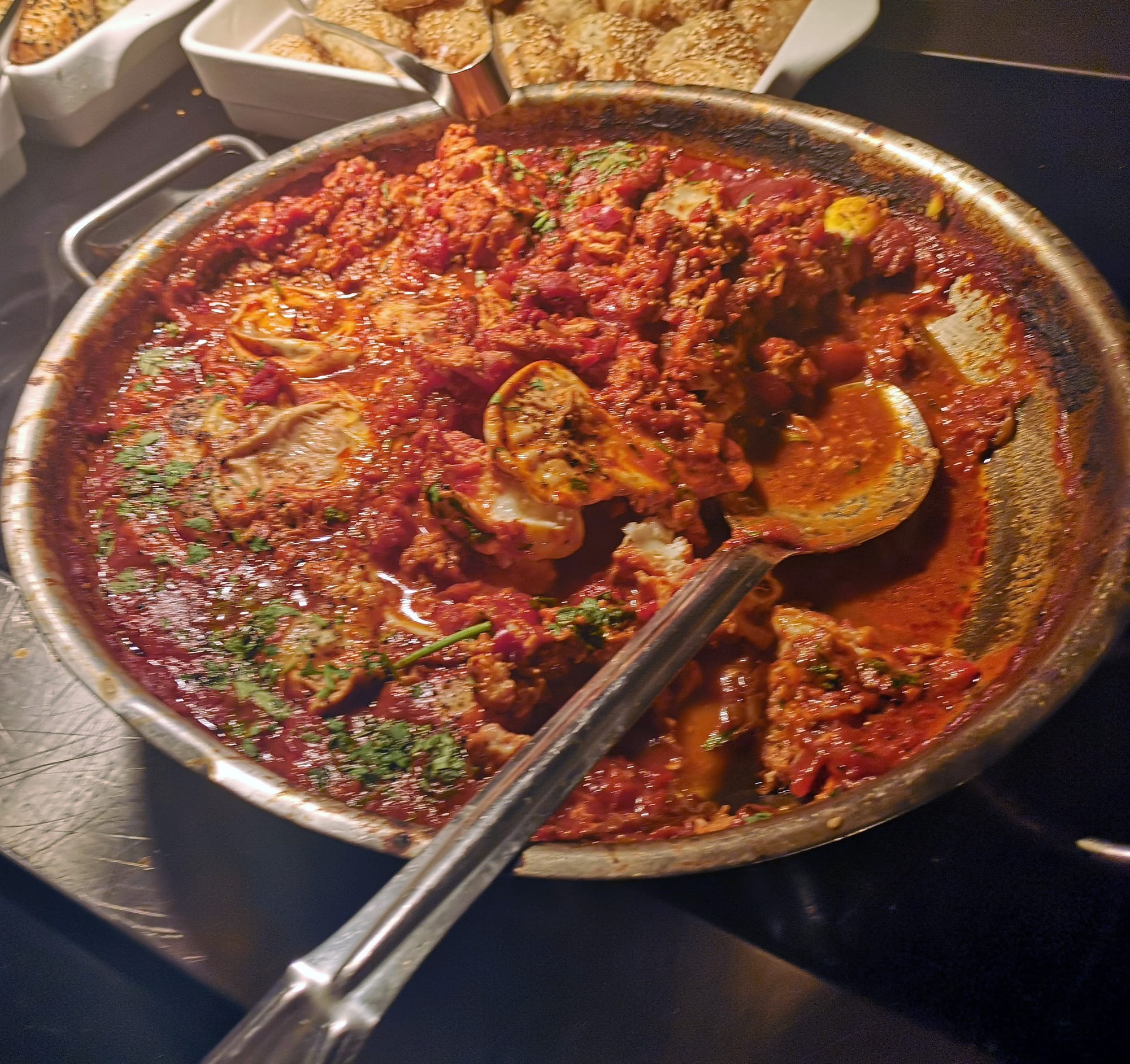 Eggs poached in a bubbling red tomato and pepper sauce in a pan