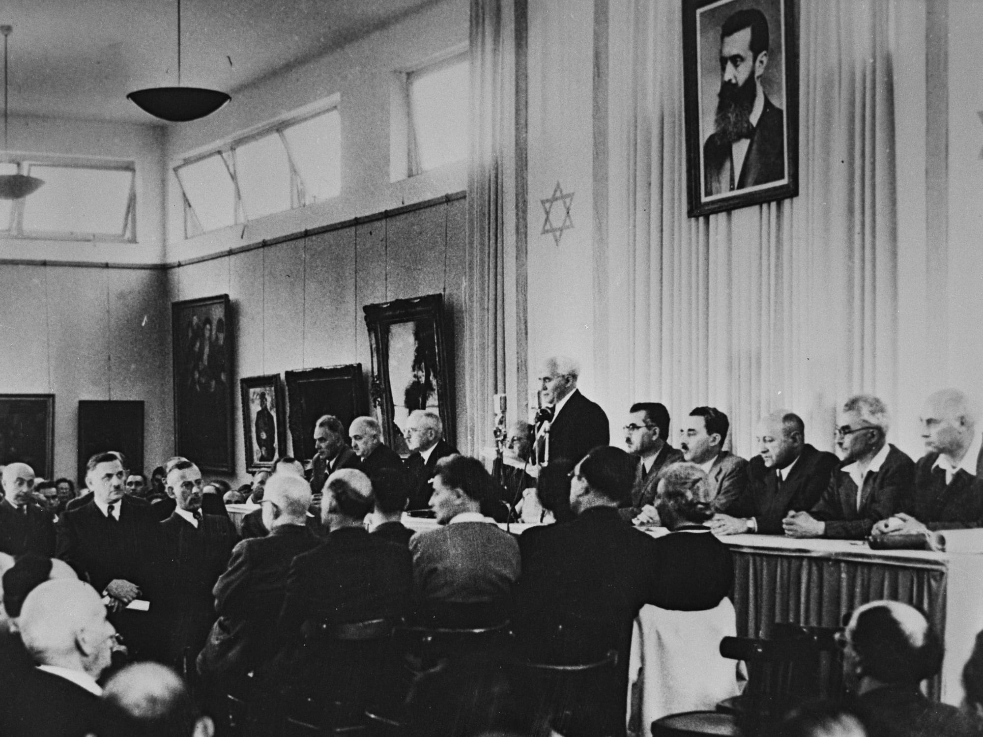 David Ben-Gurion reading Israel's Declaration of Independence beneath a portrait of Herzl, 1948
