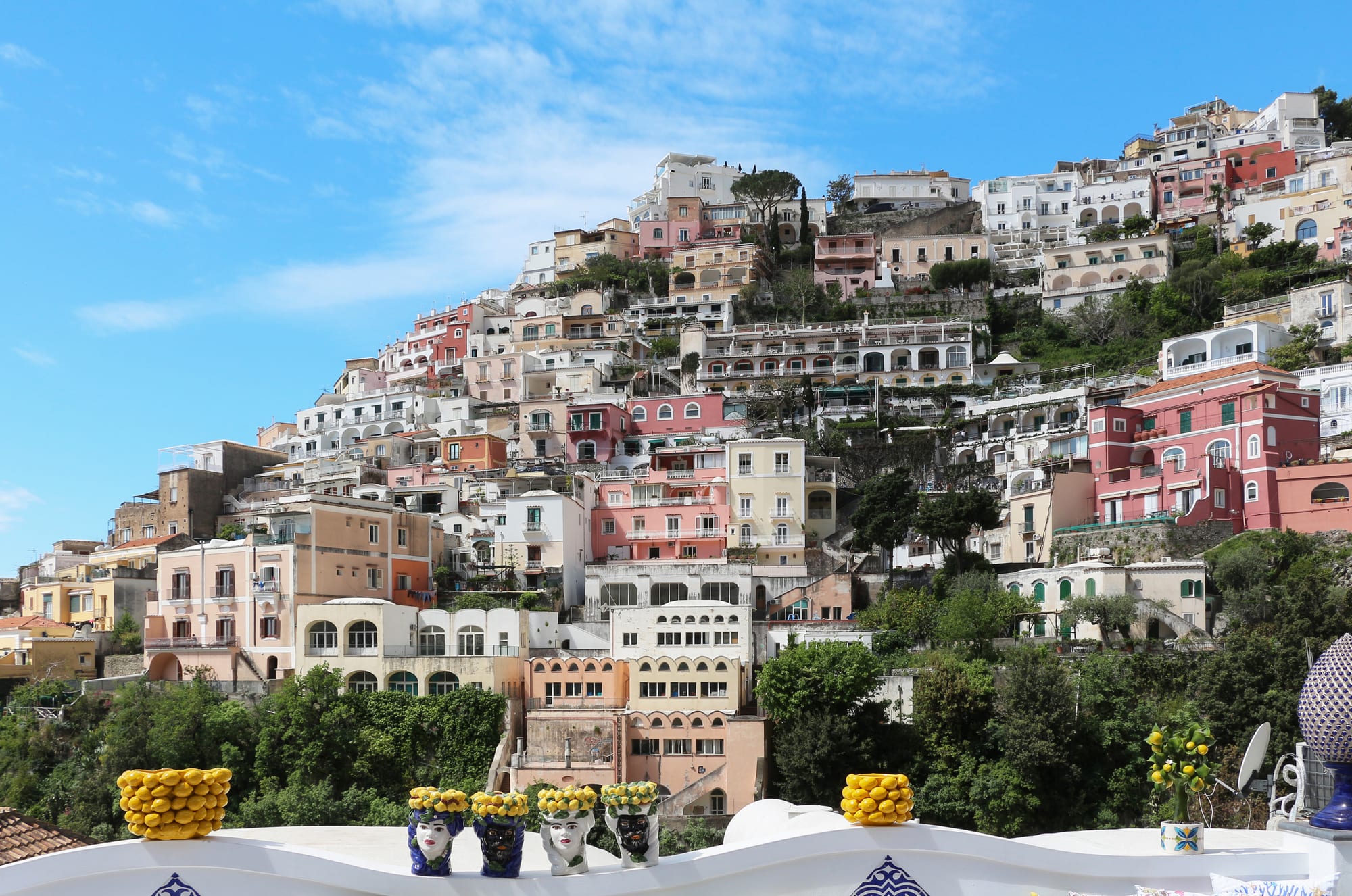 Pastel houses tumbling down a steep hillside to a small beach and turquoise sea