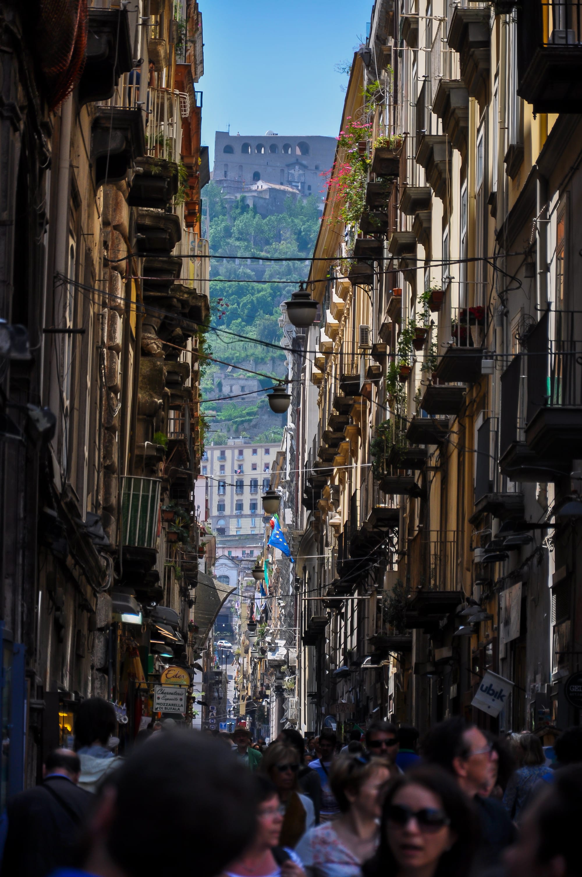 A narrow, laundry-strung street of tall old buildings in a dense city centre