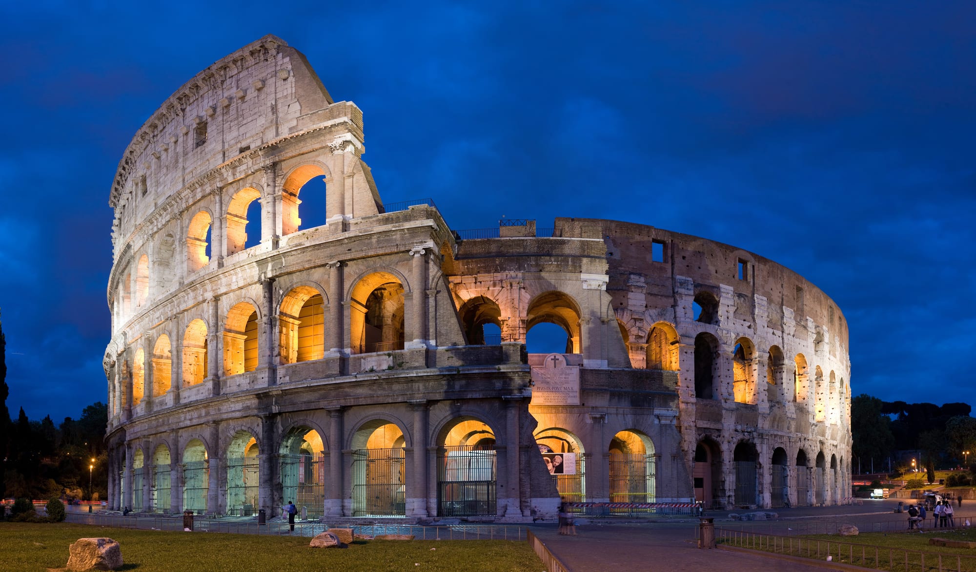 A vast ruined Roman amphitheatre of arched tiers, partly collapsed on one side
