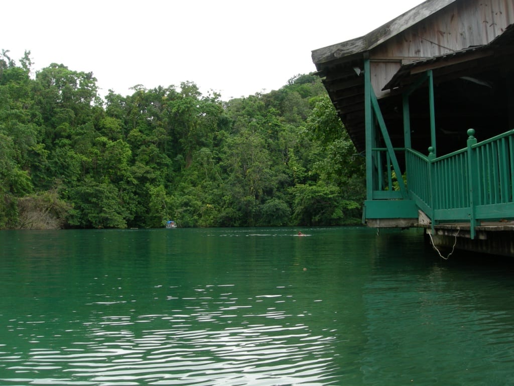 A deep blue-green lagoon ringed by jungle, meeting the sea through a narrow channel