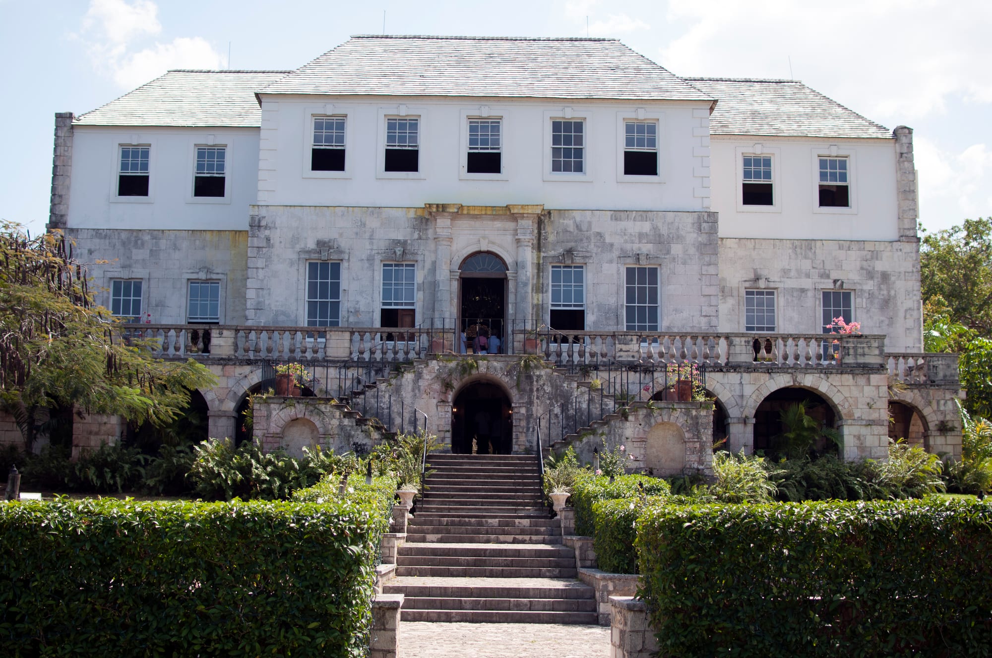 A grand white Georgian great house with a double staircase, on a manicured lawn