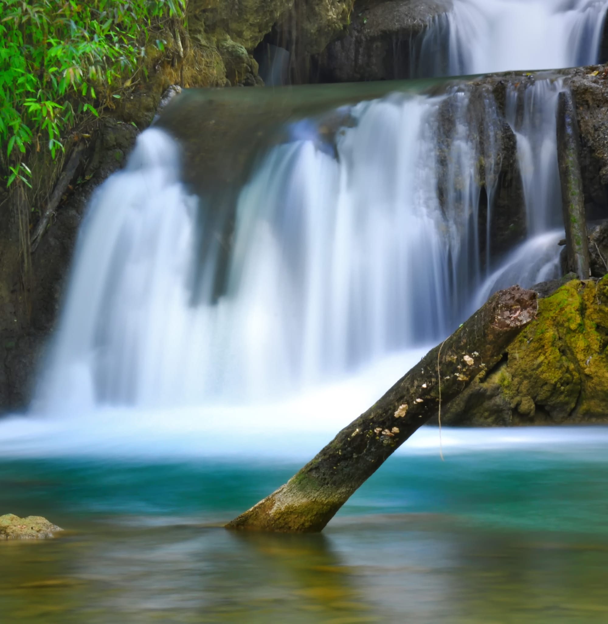 Tiered waterfalls cascading into a turquoise pool in dense green forest