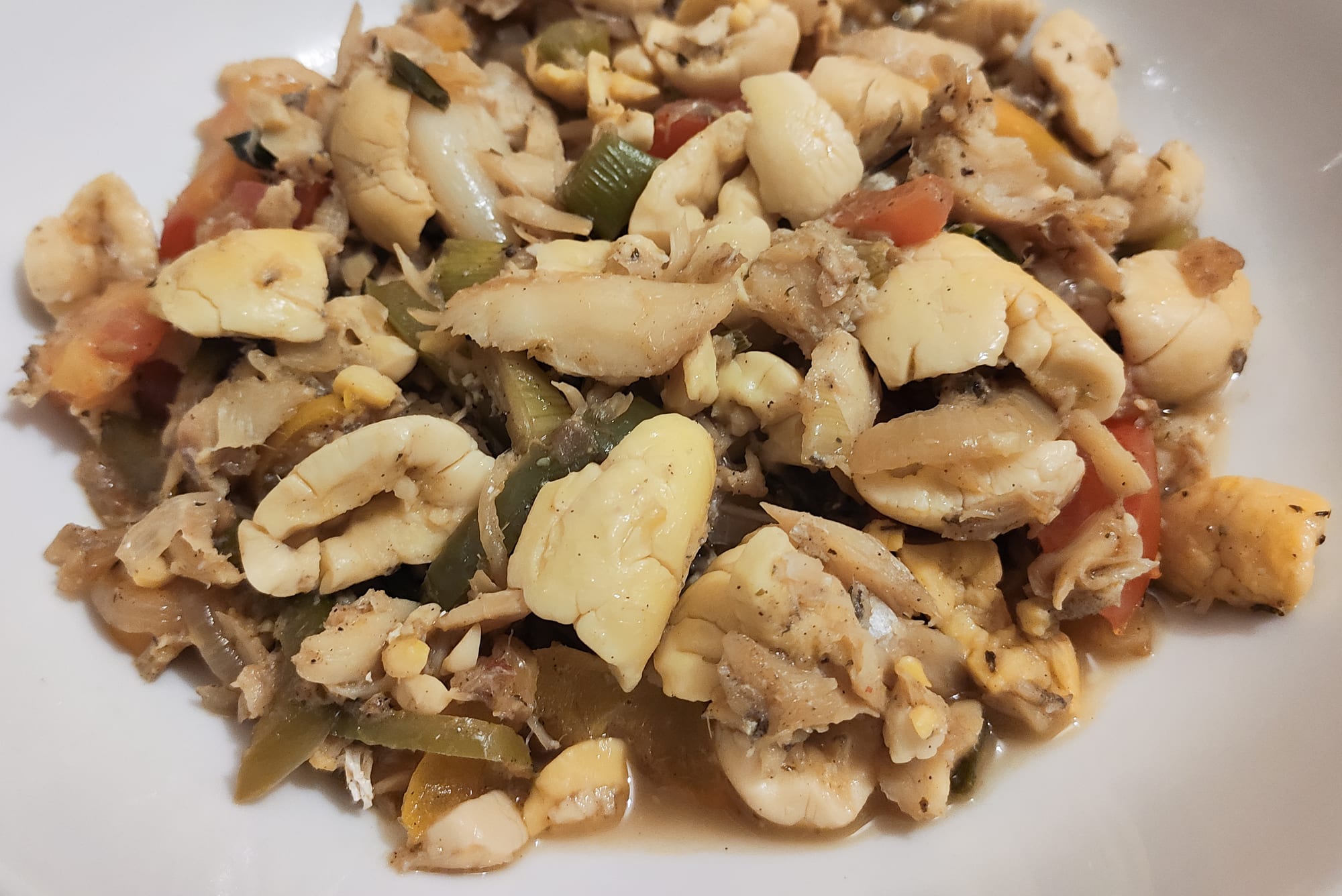 A plate of yellow, egg-like ackee mixed with flaked fish and peppers