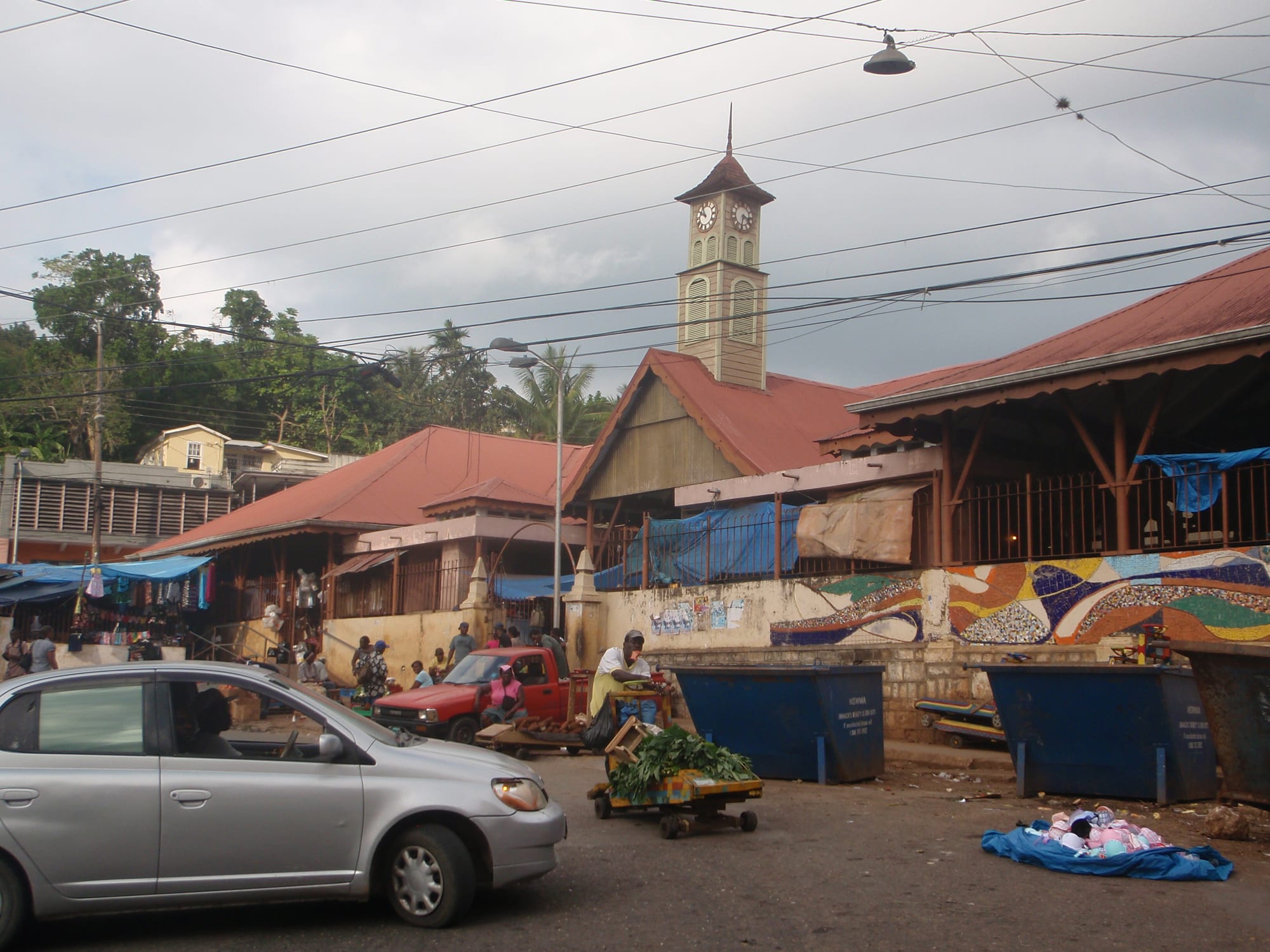 A market street in Brown's Town, Jamaica, with stalls, a red pickup truck and a colonial-era clock tower