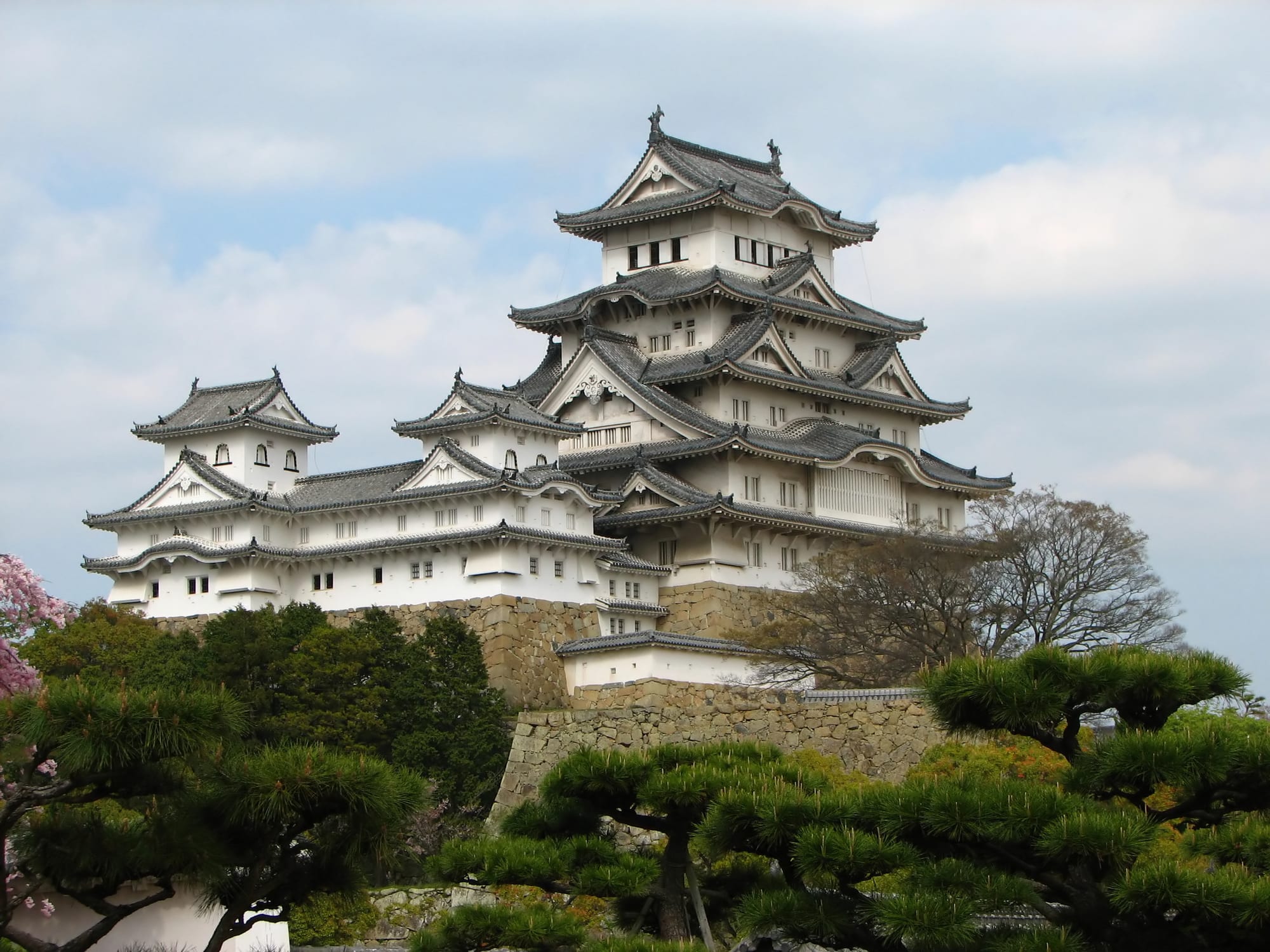 A large white multi-tiered castle keep with sweeping roofs on a stone base