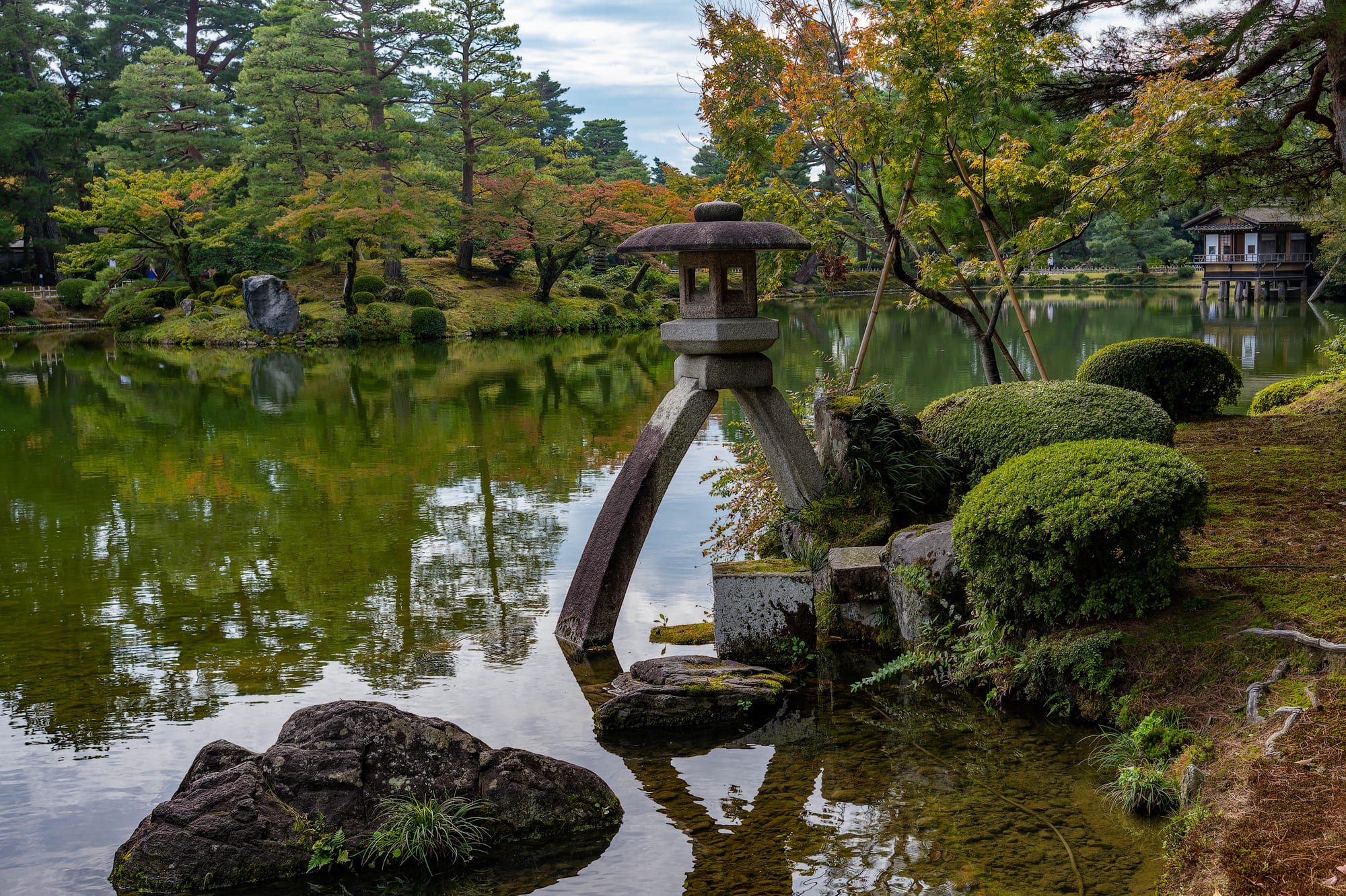 A classical landscape garden with a stone lantern, curved pine, and pond