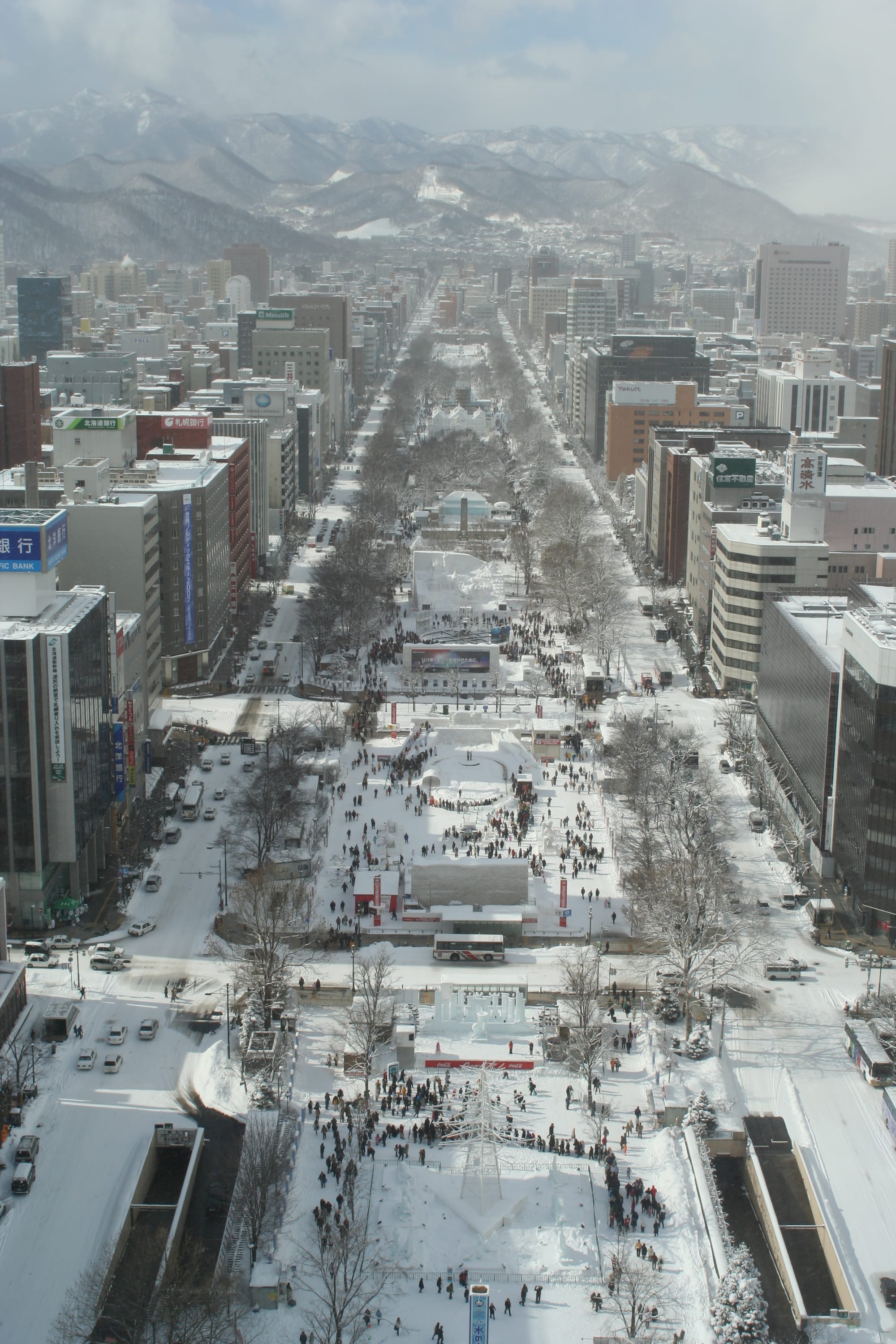 An aerial view of Odori Park filled with snow sculptures and crowds during the festival