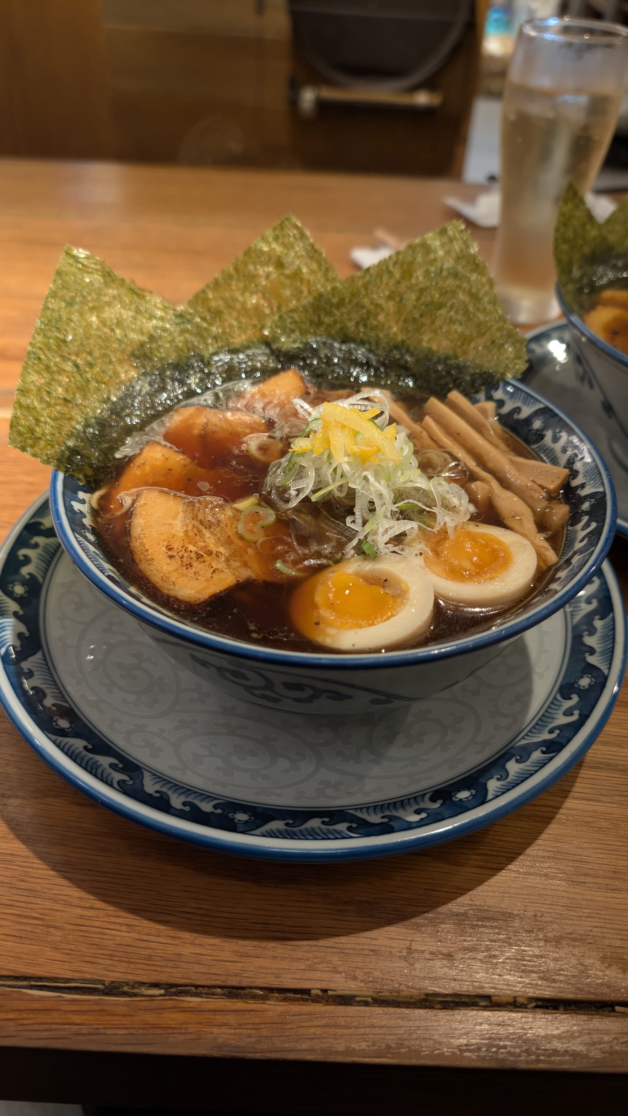 A bowl of noodle soup topped with sliced meat, egg and vegetables