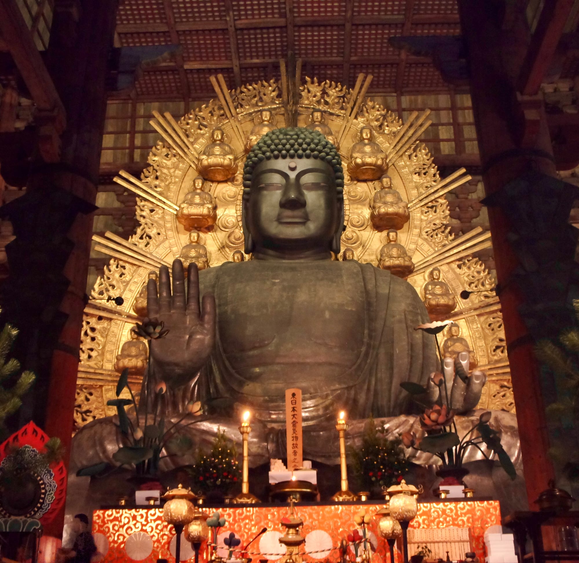 A colossal bronze seated Buddha inside a vast wooden temple hall