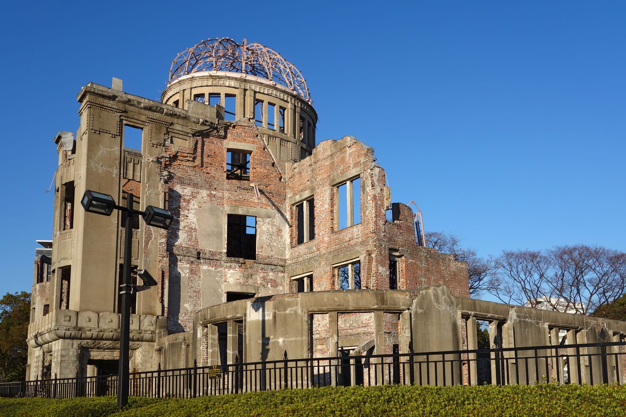The skeletal ruined dome of a building preserved beside a river in Hiroshima