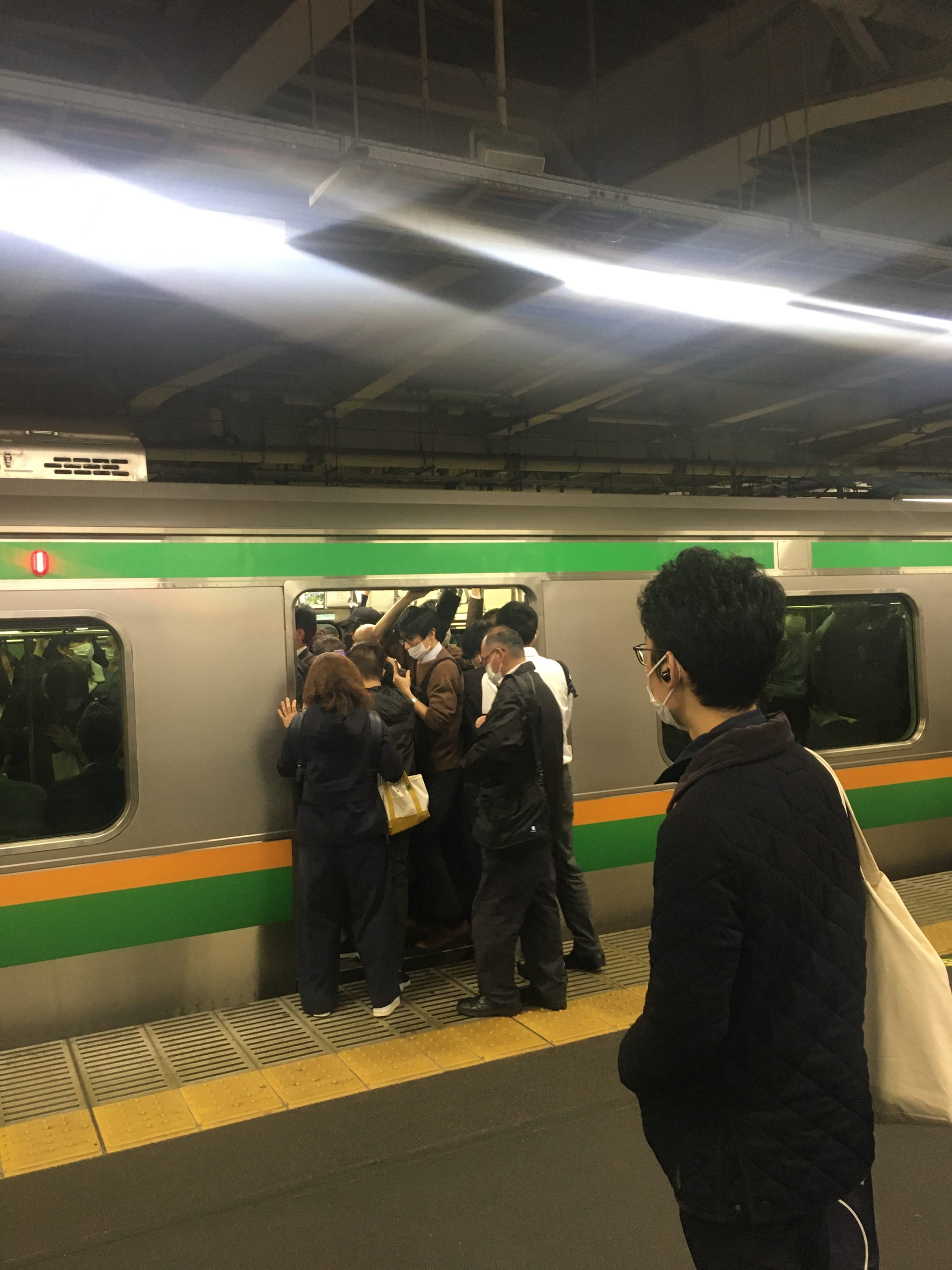 A densely packed train platform at Shinagawa Station in Tokyo during evening rush hour
