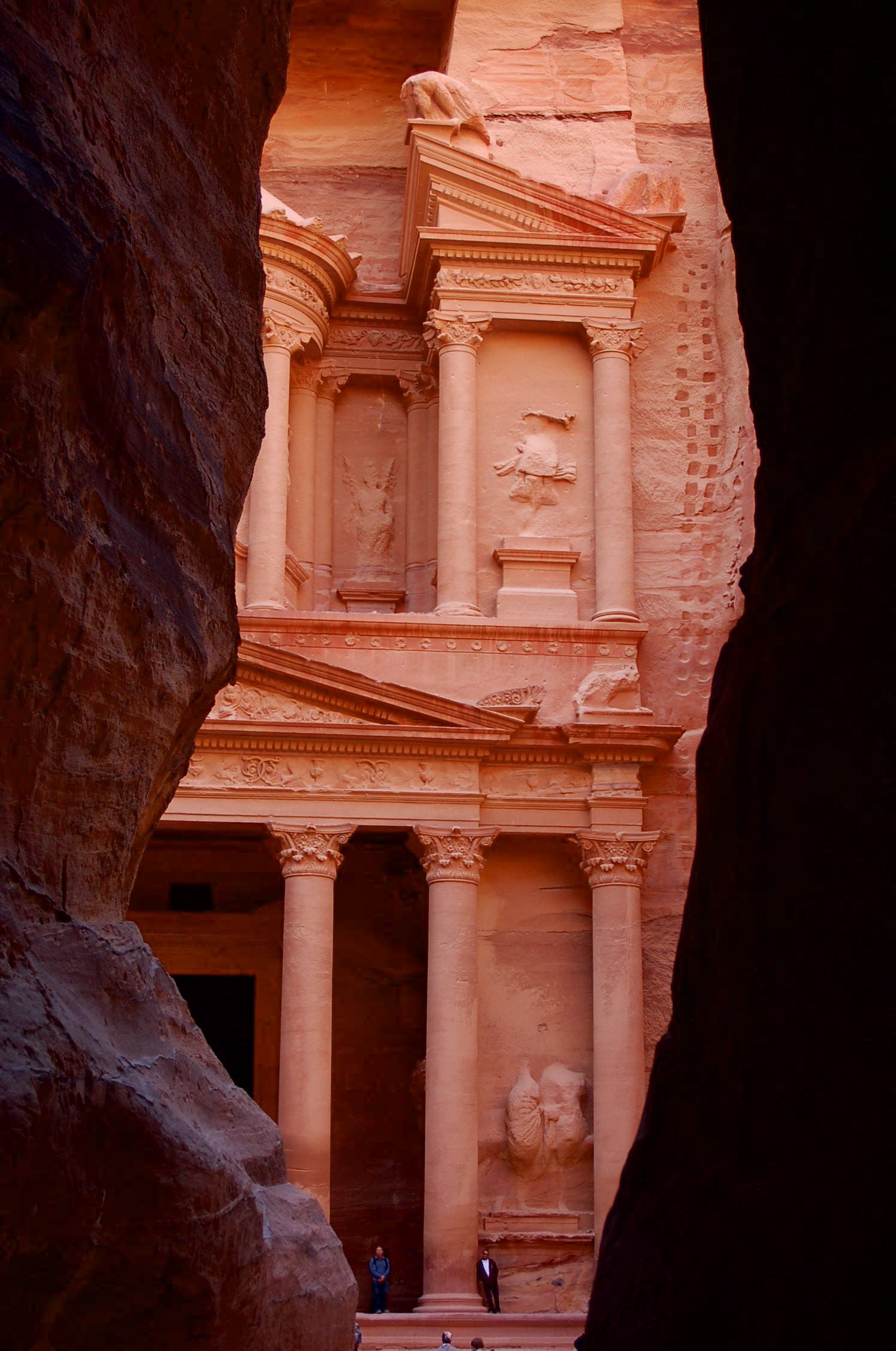 The narrow rock canyon of the Siq opening onto a glimpse of the carved Treasury facade