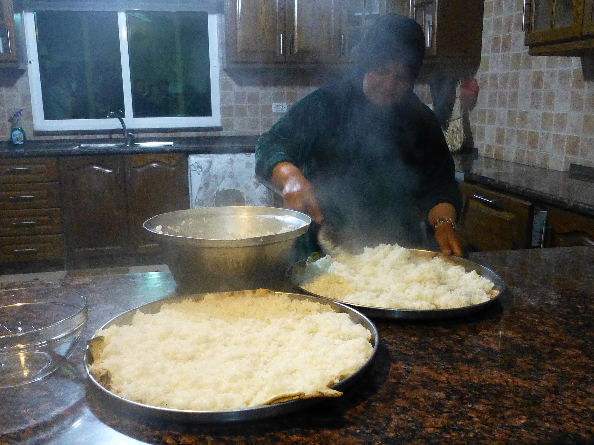 A large platter of rice topped with meat and a pale sauce, garnished with nuts