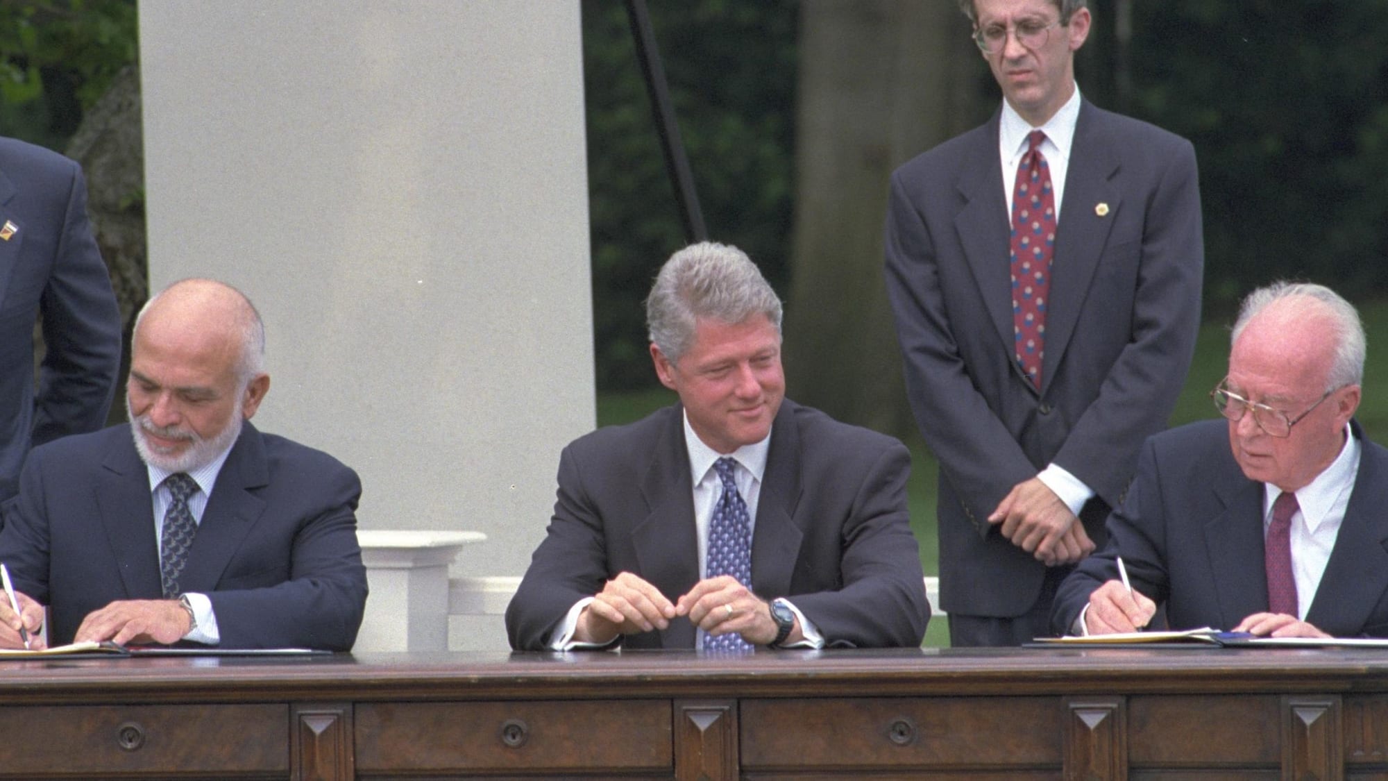 King Hussein and Yitzhak Rabin at a desk signing documents at the 1994 peace ceremony
