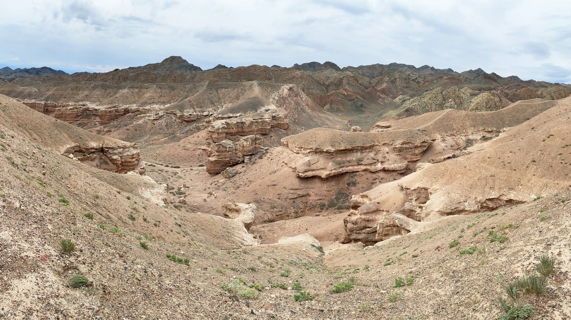 Eroded red rock towers and cliffs in a dry canyon under a blue sky