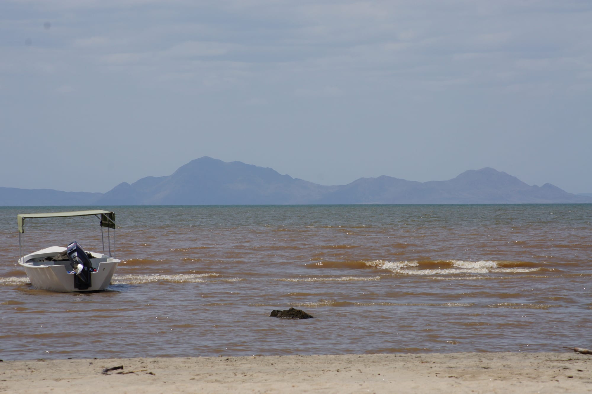 A vast jade-green lake meeting a barren volcanic desert shore