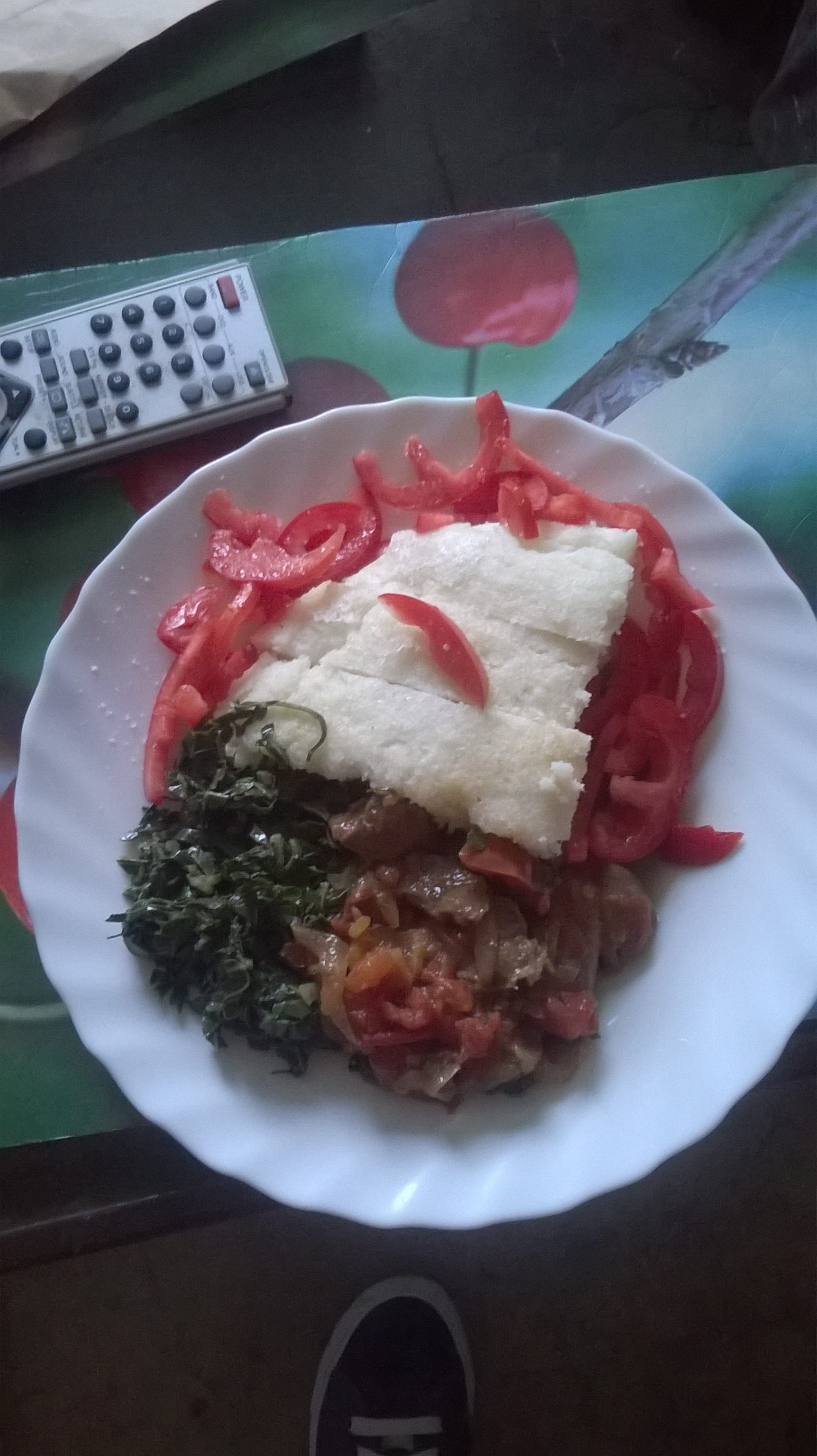A mound of firm white maize dough served with beef stew and greens