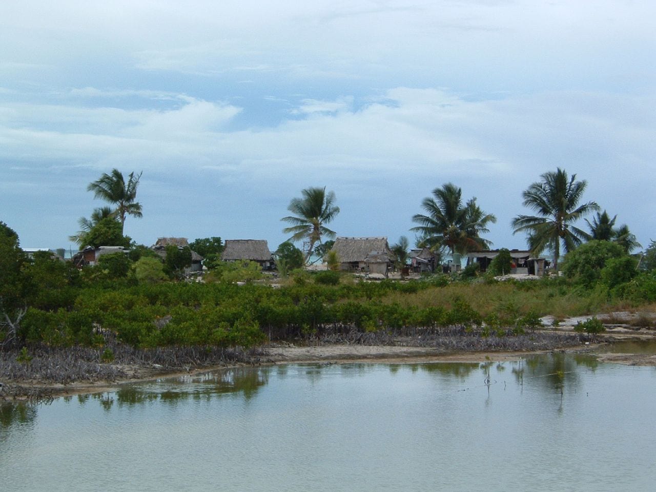 Thatched-roof houses along a lagoon shore on a narrow strip of land