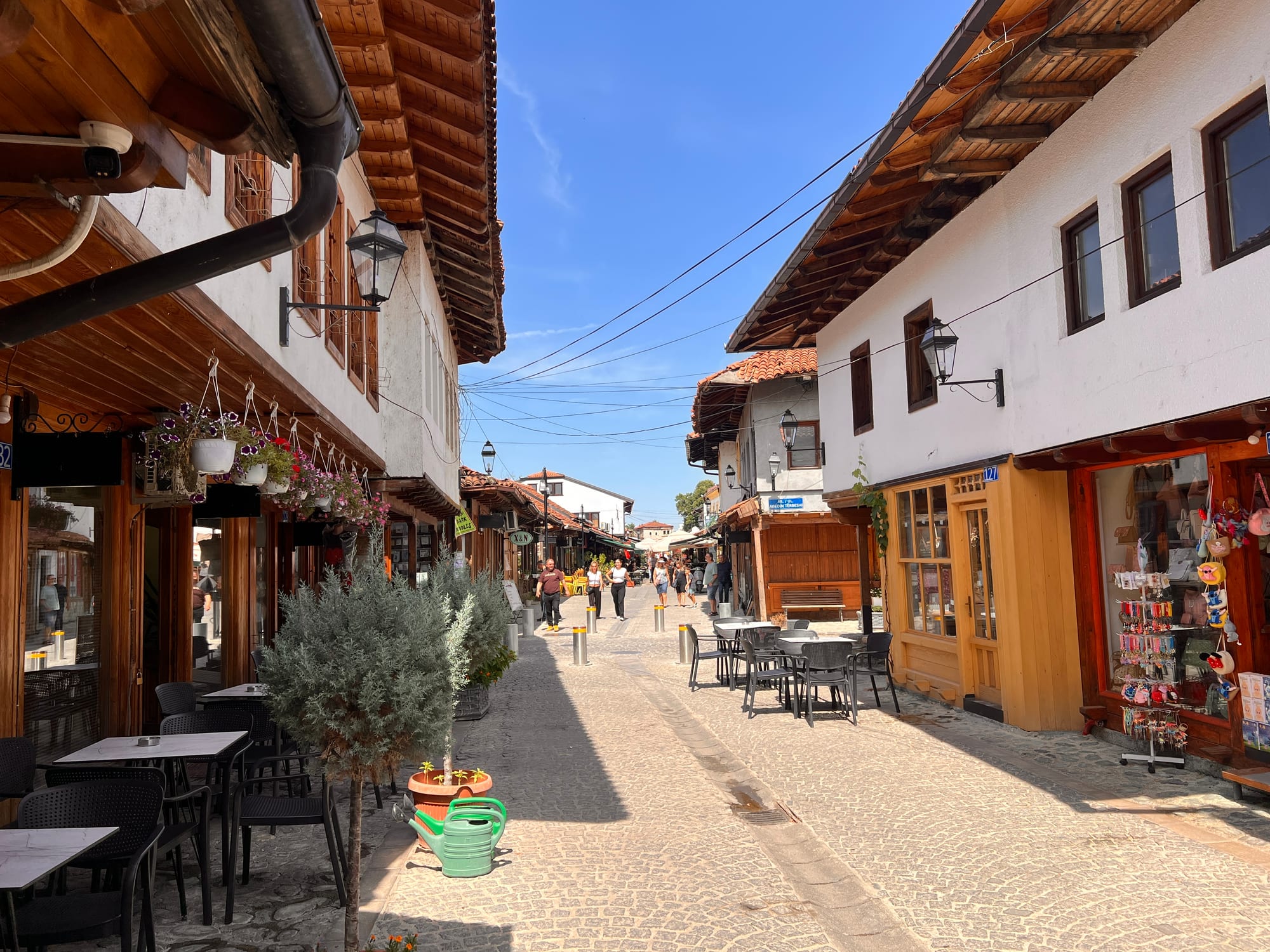 A cobbled lane lined with low white-and-timber shops under a covered walkway