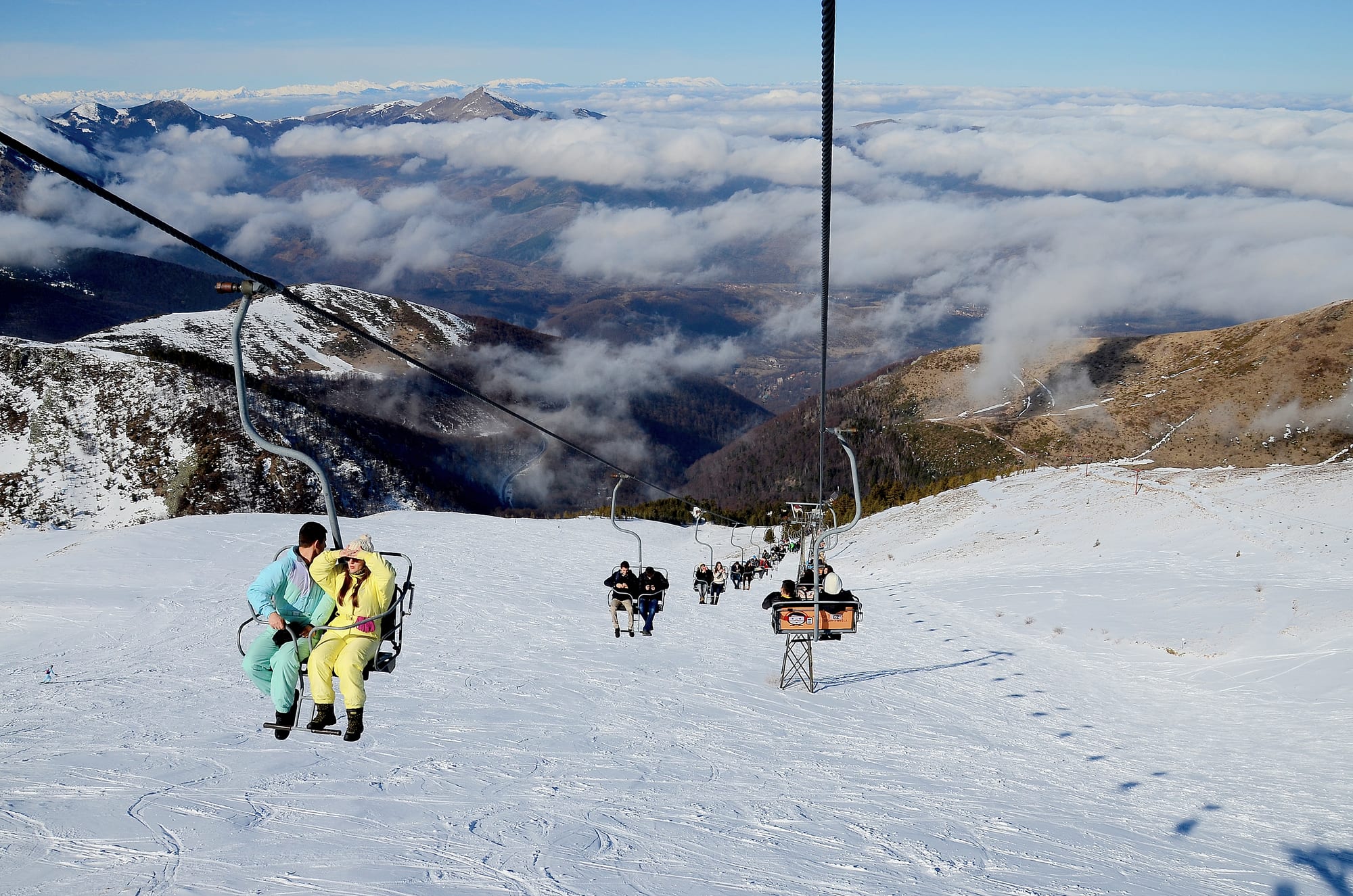 A ski resort of runs and lifts on open slopes below rounded snowy peaks
