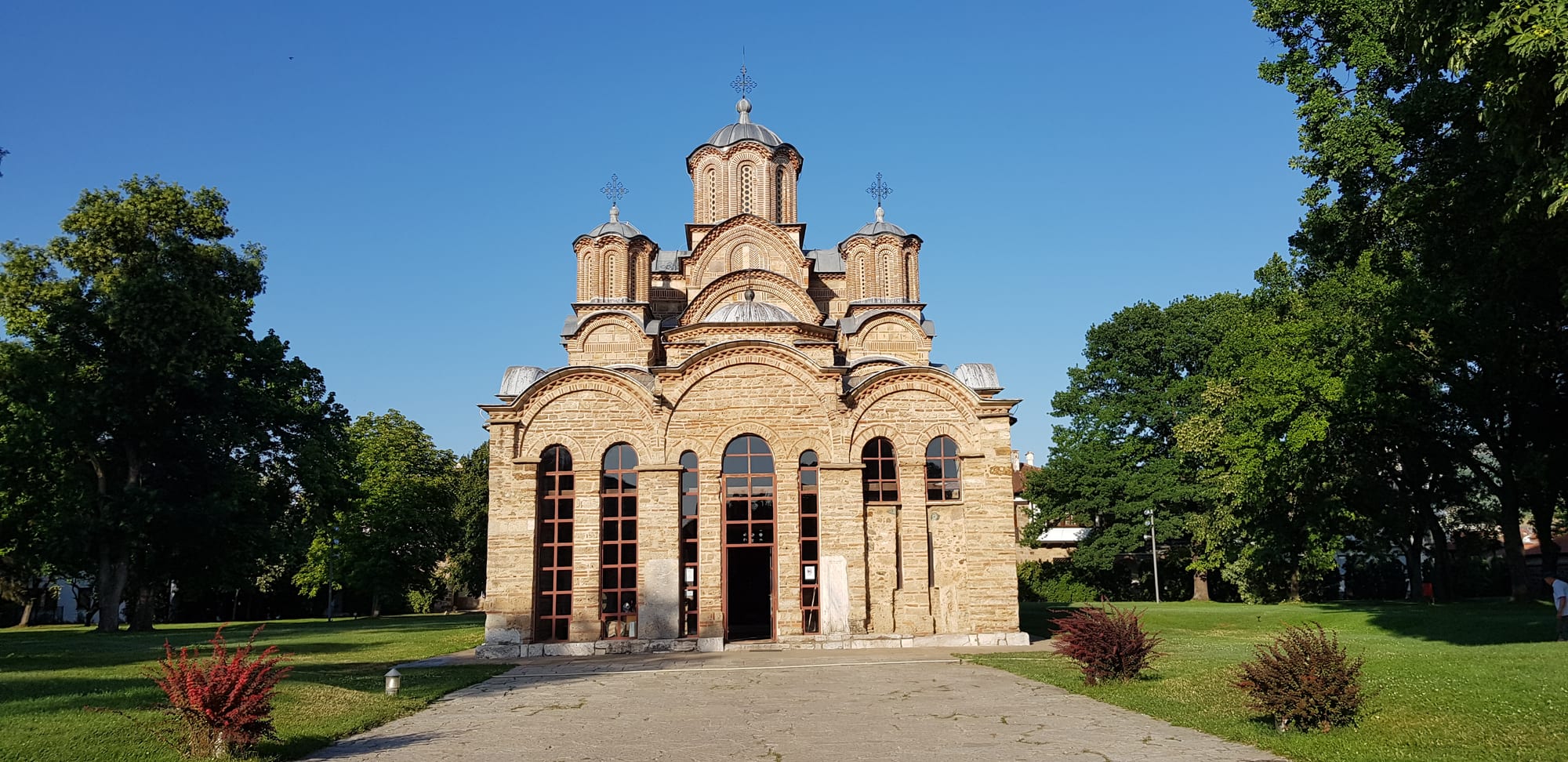 A compact medieval Byzantine church with five domes on a stepped roofline, in a walled yard