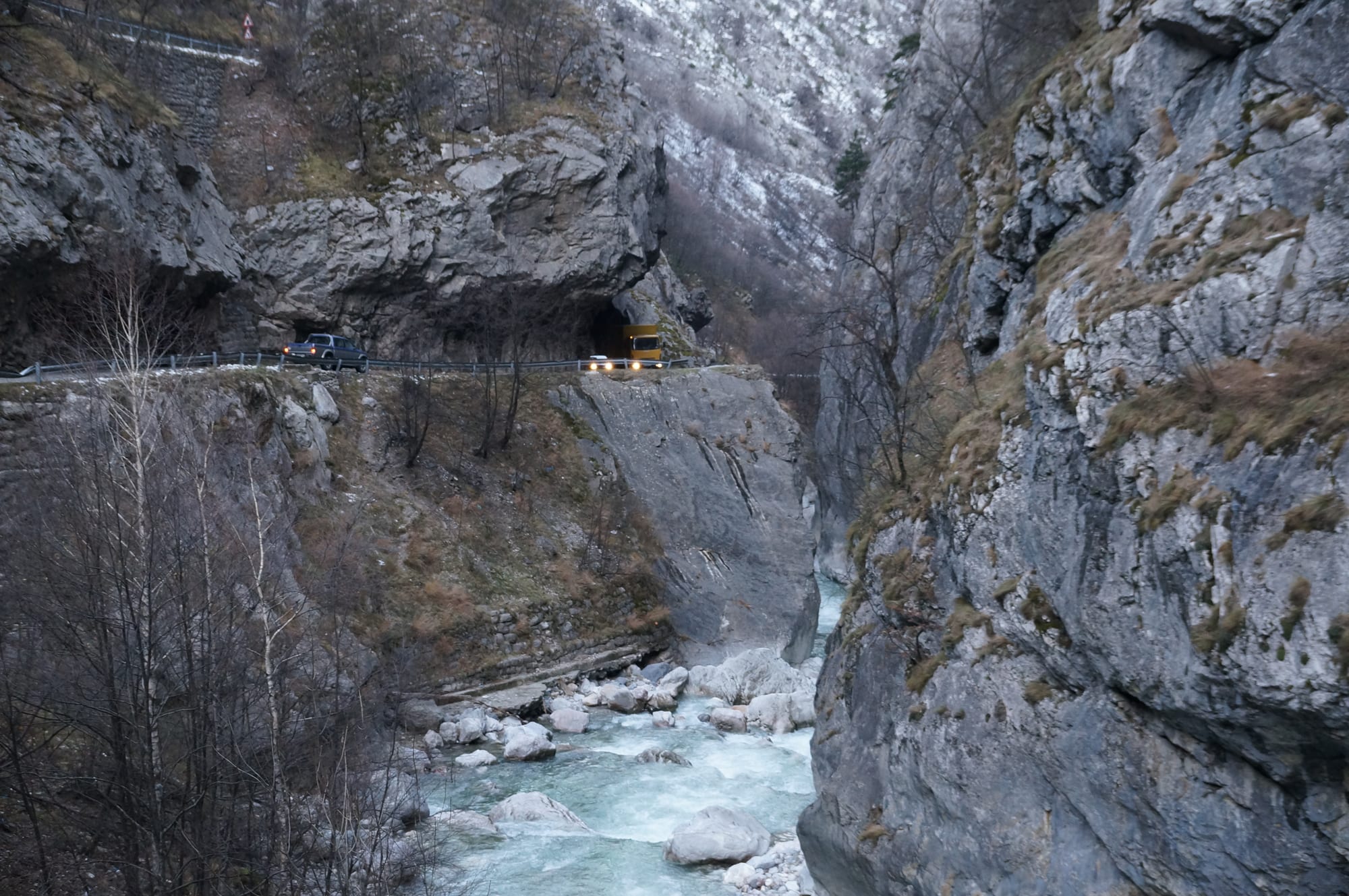 A deep, narrow river gorge with sheer grey rock walls and pine slopes above