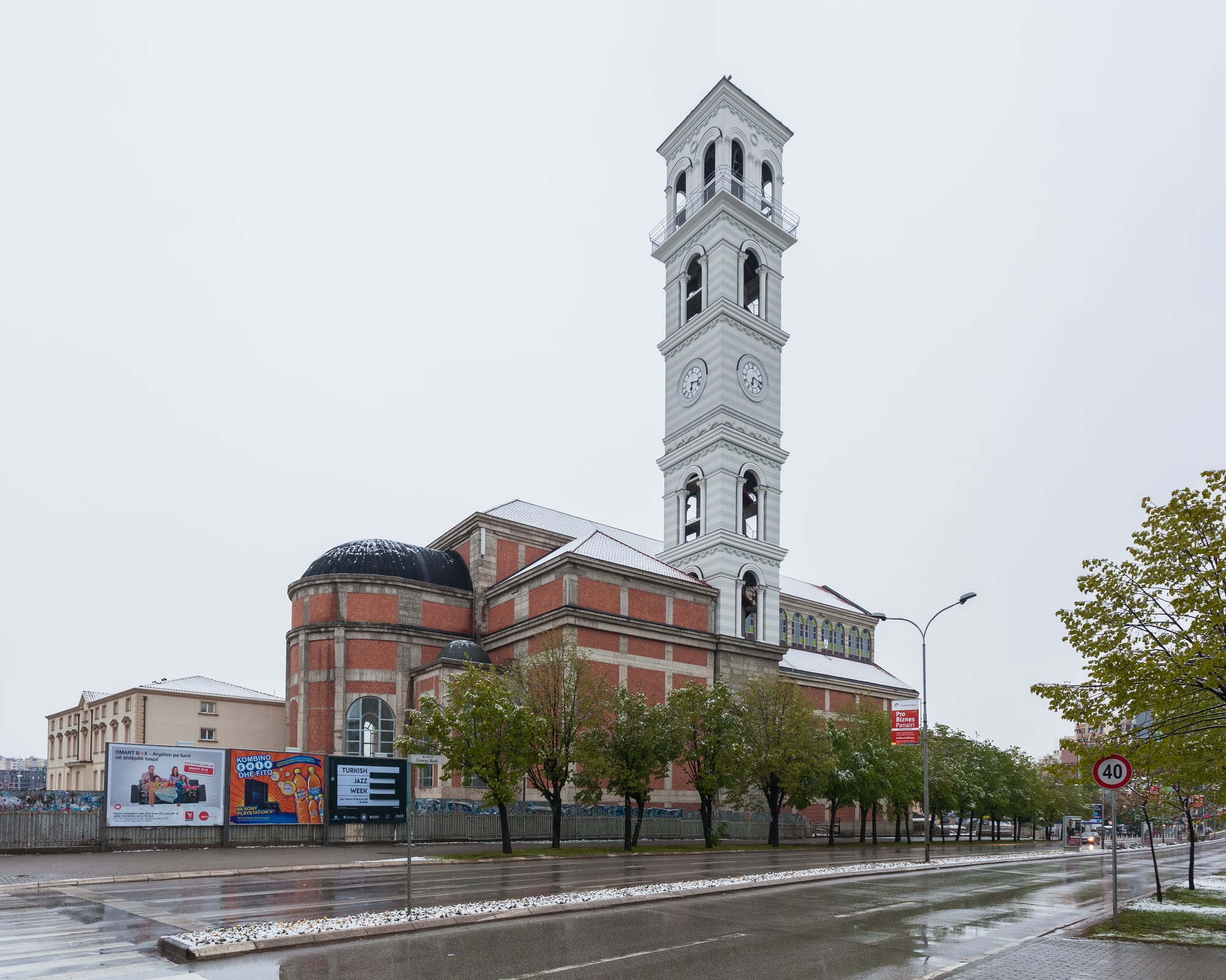 A large modern stone cathedral with a tall bell tower in a city square