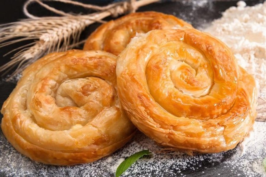 A tray of golden, layered filo pastry cut into portions