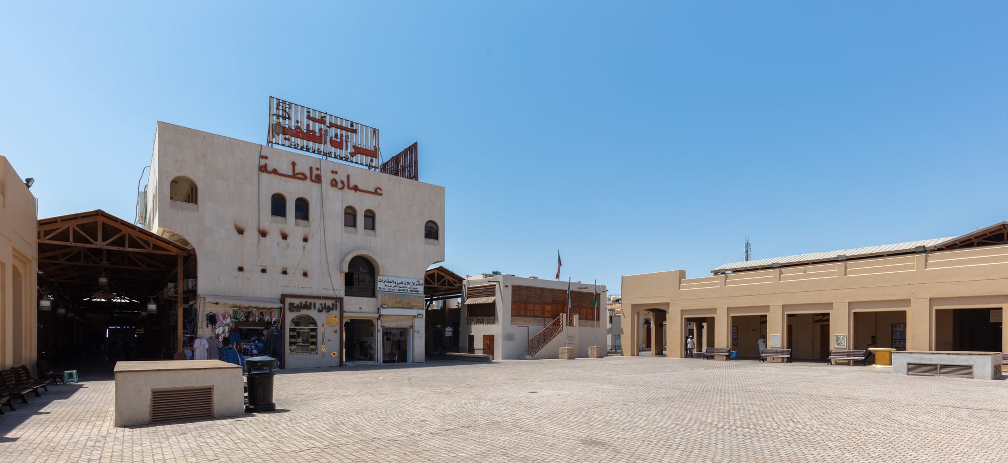 A covered market lane of small shops selling spices, textiles, and goods