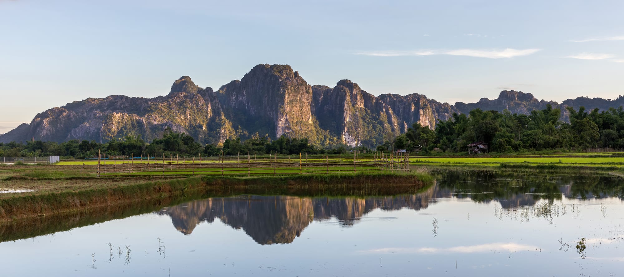Jagged limestone karst peaks reflected in a still river at golden hour