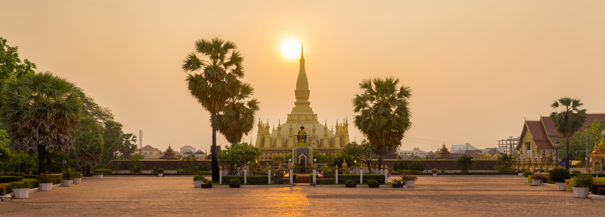 A tall gold-covered stupa with tiered spires at sunrise