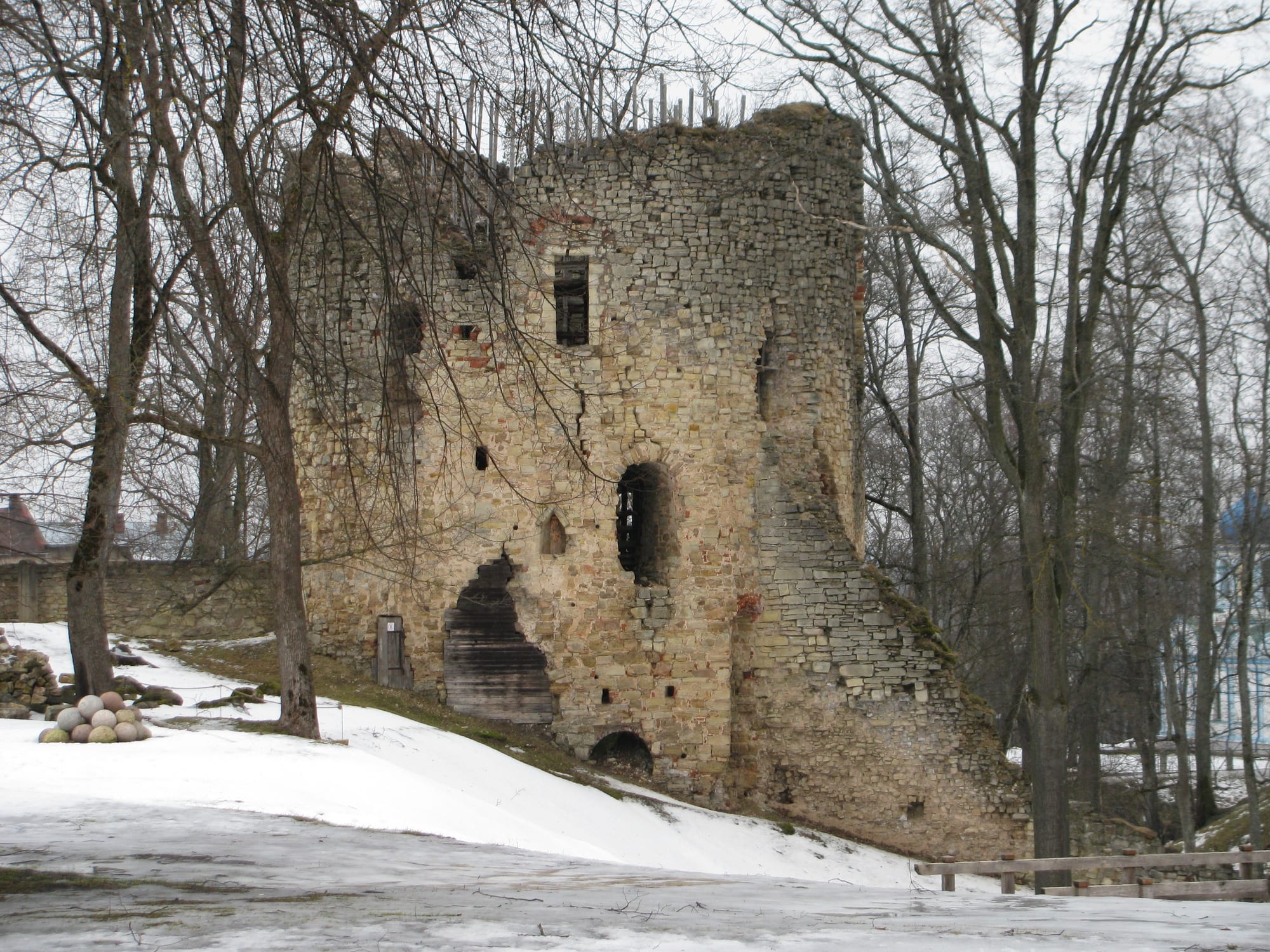 Round medieval stone castle towers and ruined walls beside a small lake