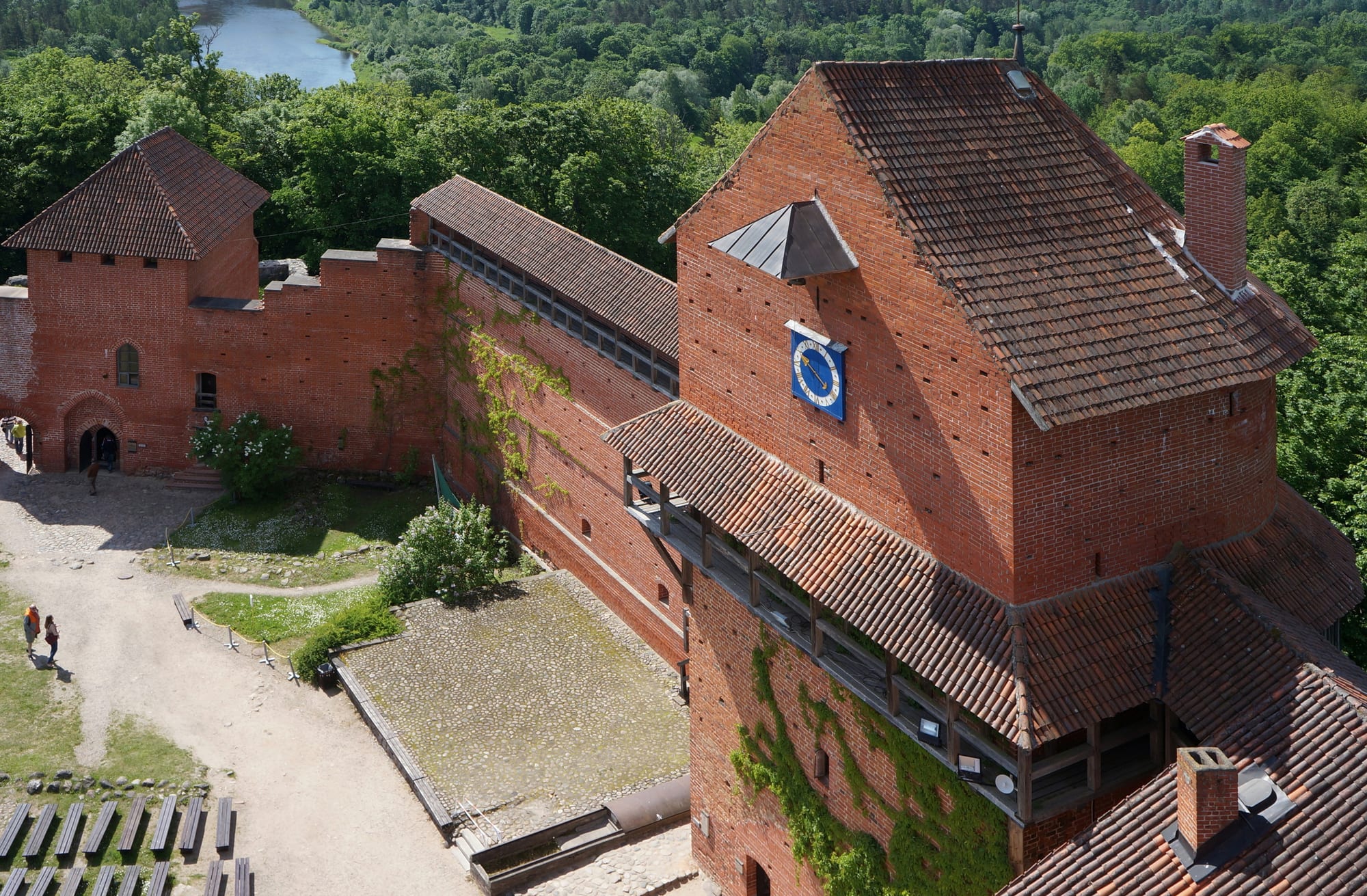 A restored brick medieval castle tower and walls above a green river valley