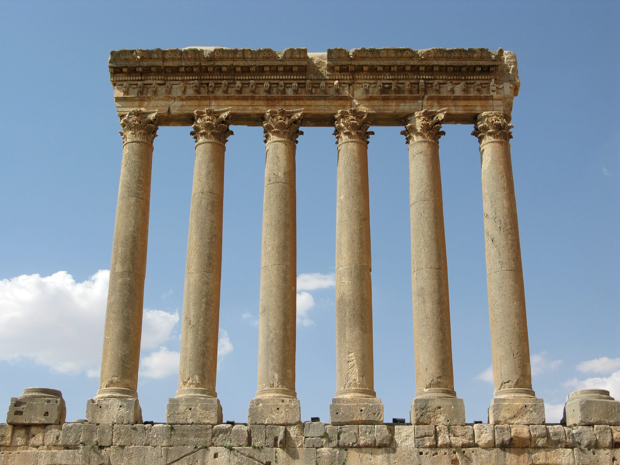 A row of enormous stone Corinthian columns standing among ruined temple foundations