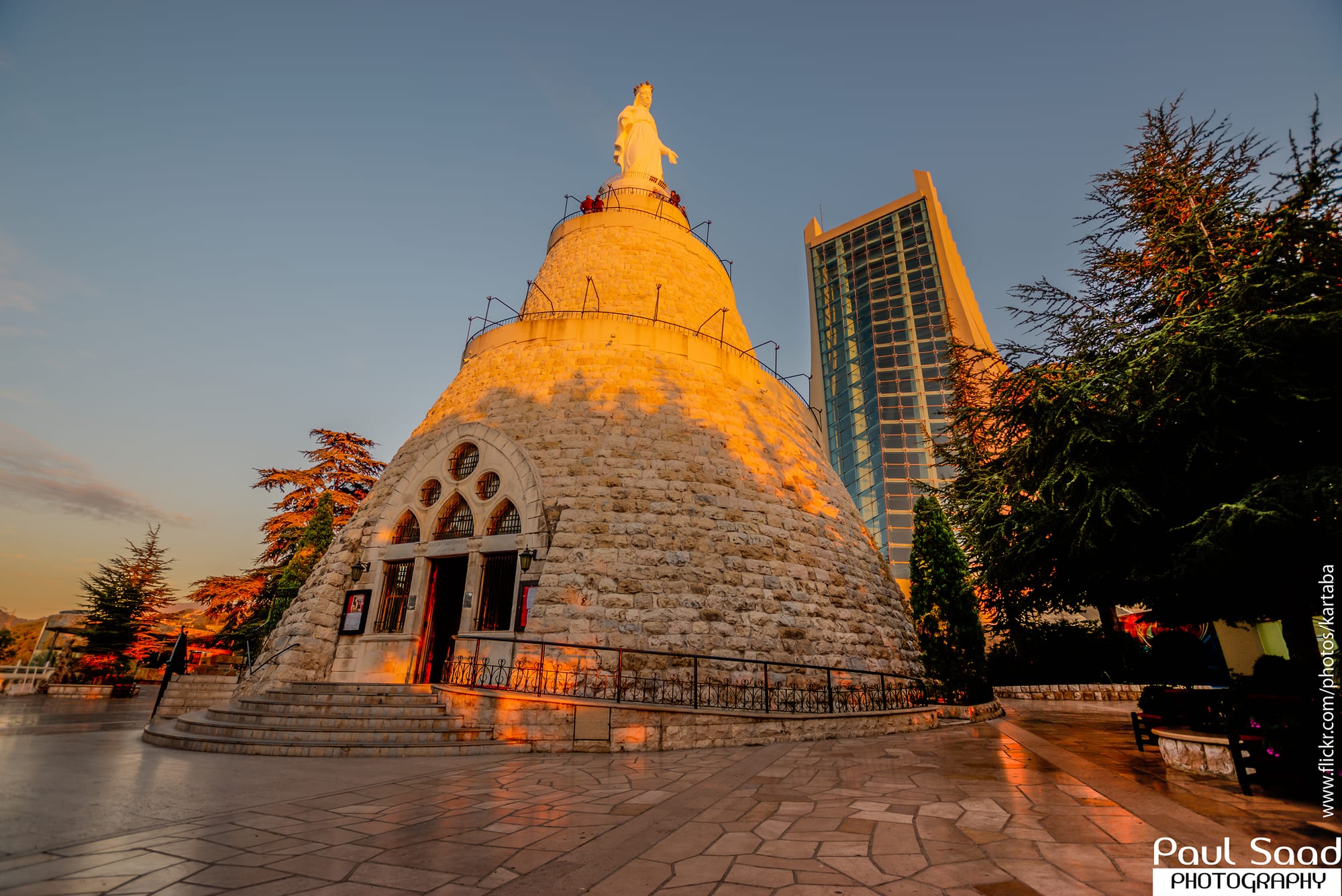 A huge white statue of the Virgin Mary on a hilltop pedestal overlooking the coast