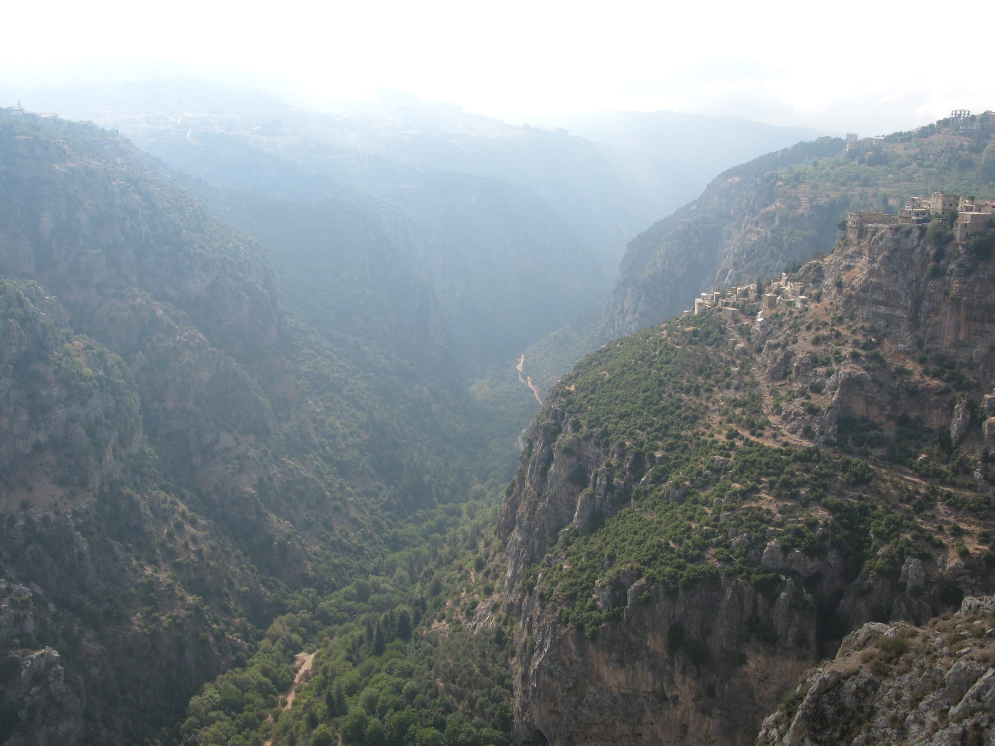 A deep, steep-sided green canyon with monasteries and villages perched on its slopes