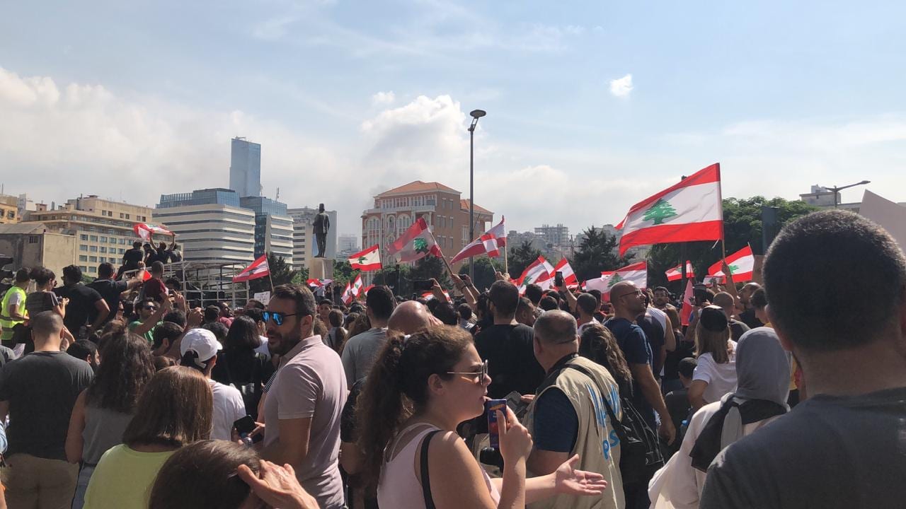 A large crowd of protesters with Lebanese flags filling a Beirut street at night in 2019