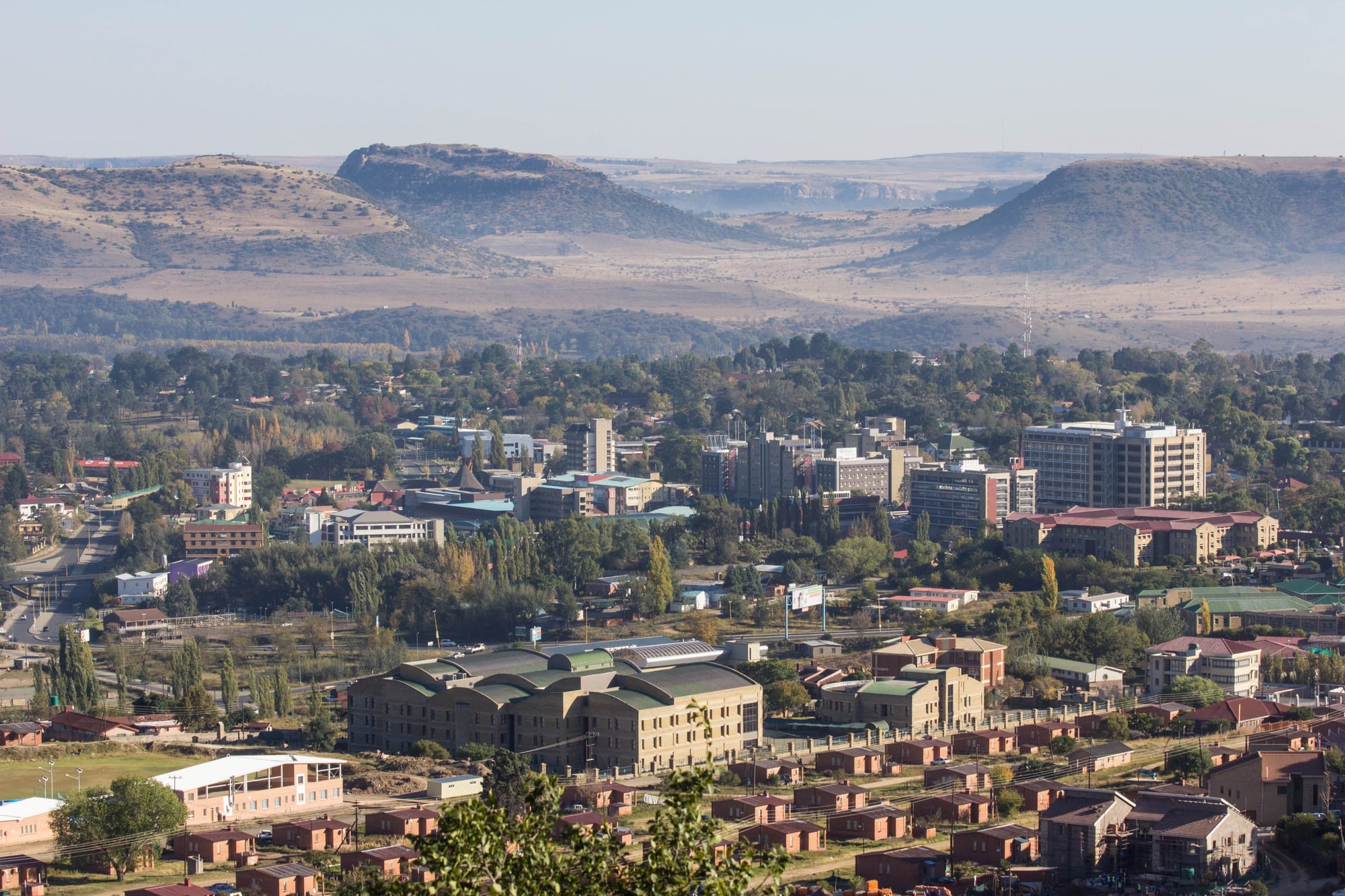 A low-rise city spread across a valley with hills in the background