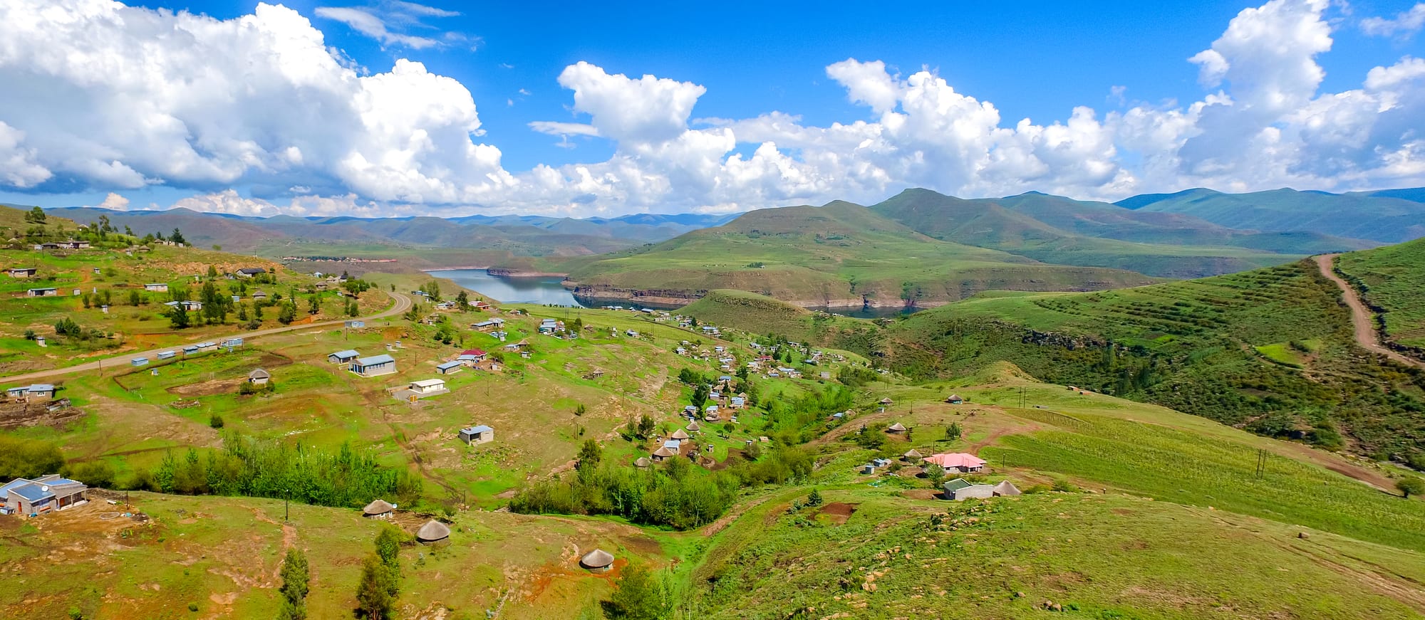 A small village of round stone huts on a green ridge among high, bare mountains