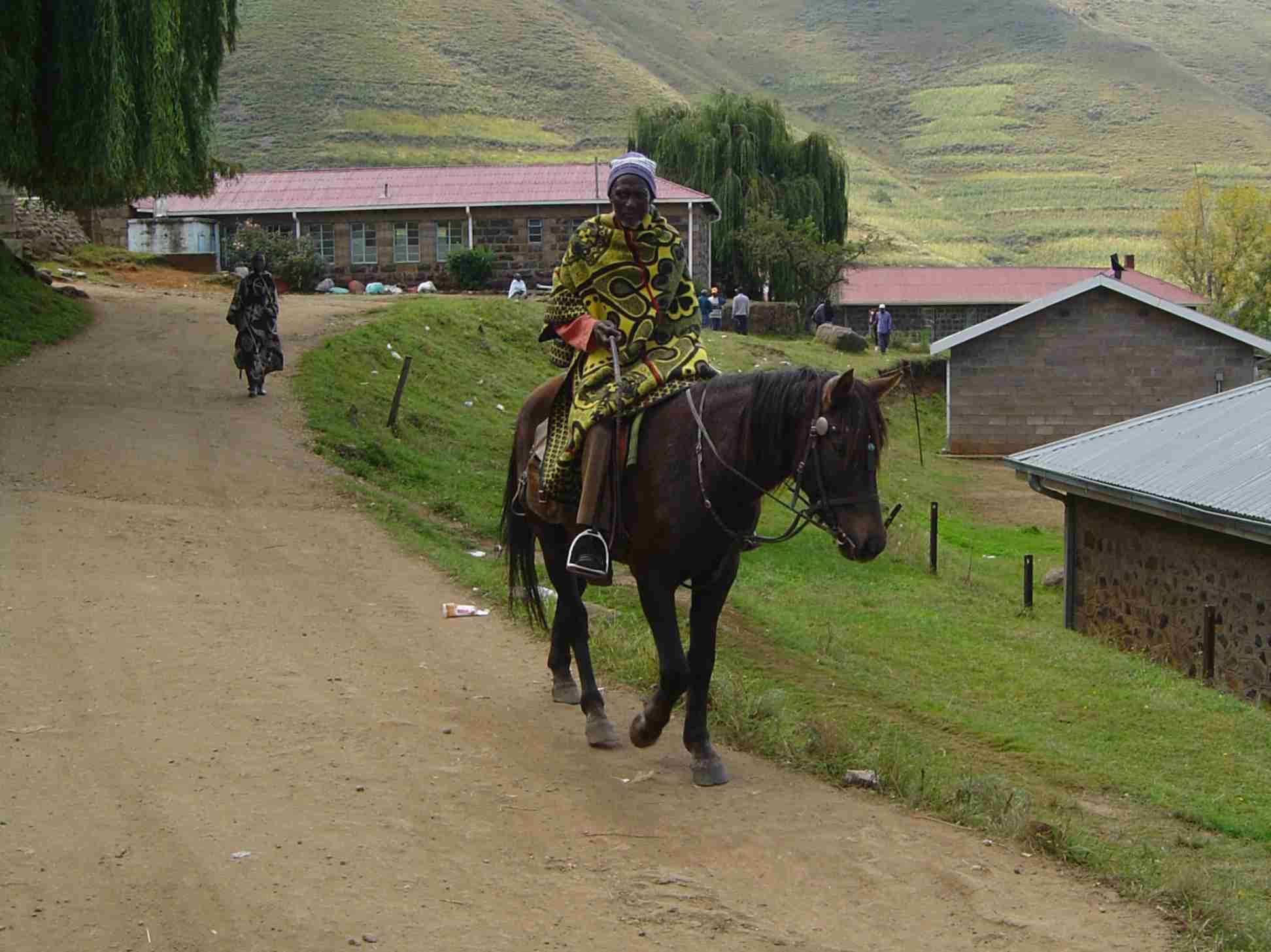 A man on horseback wrapped in a patterned Basotho blanket in a mountain landscape