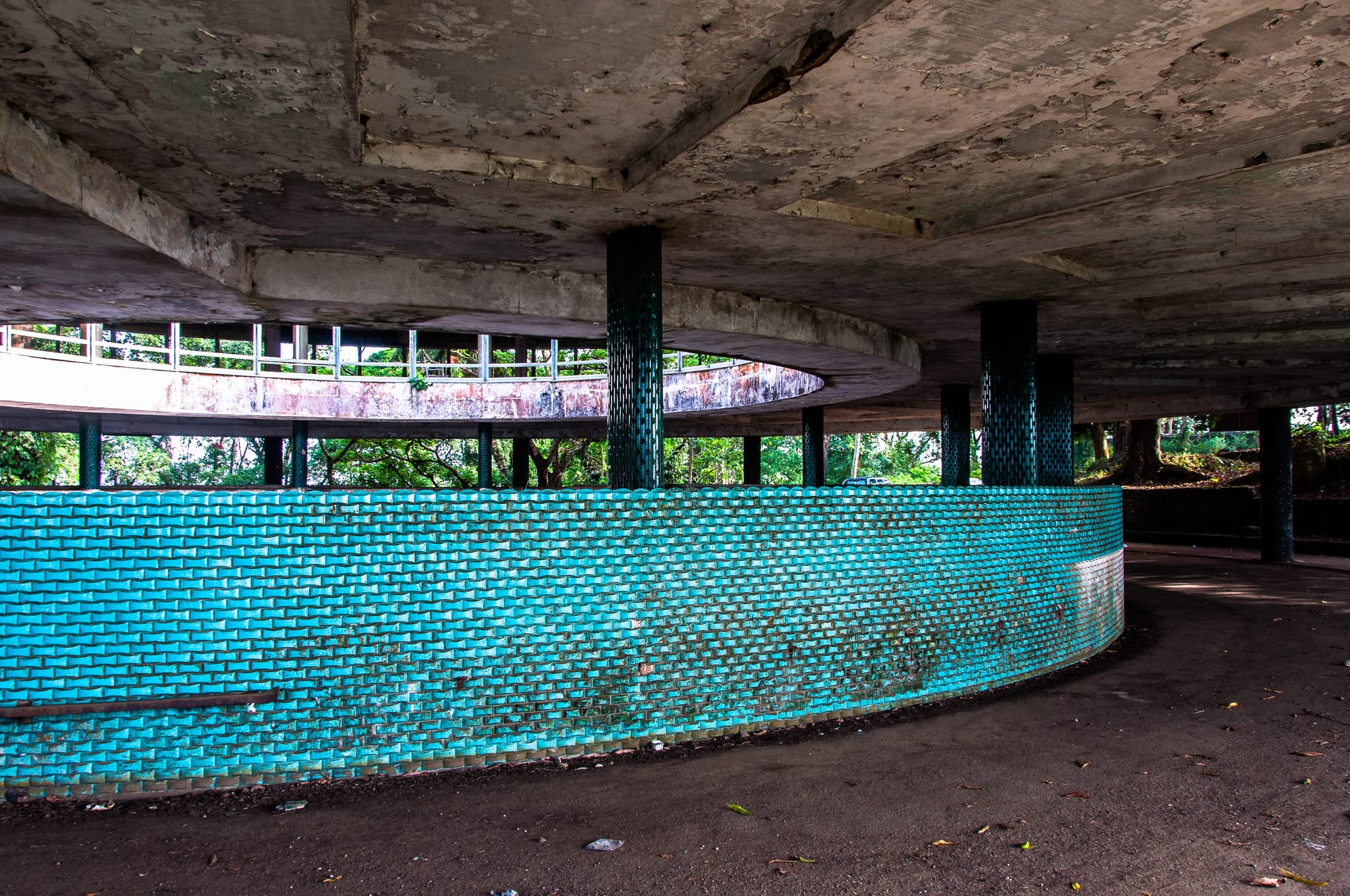 A crumbling modernist hotel building overgrown with vegetation on a hilltop