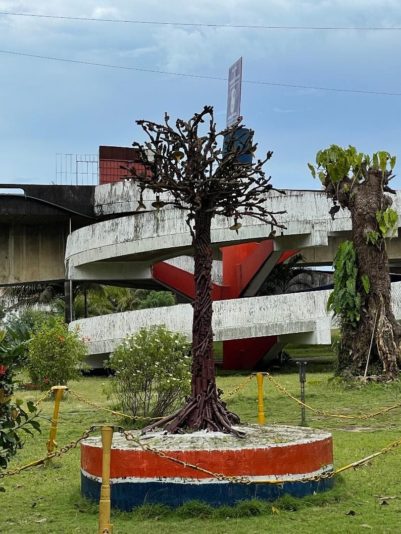 A stone monument and small park on a wooded island in a city lagoon